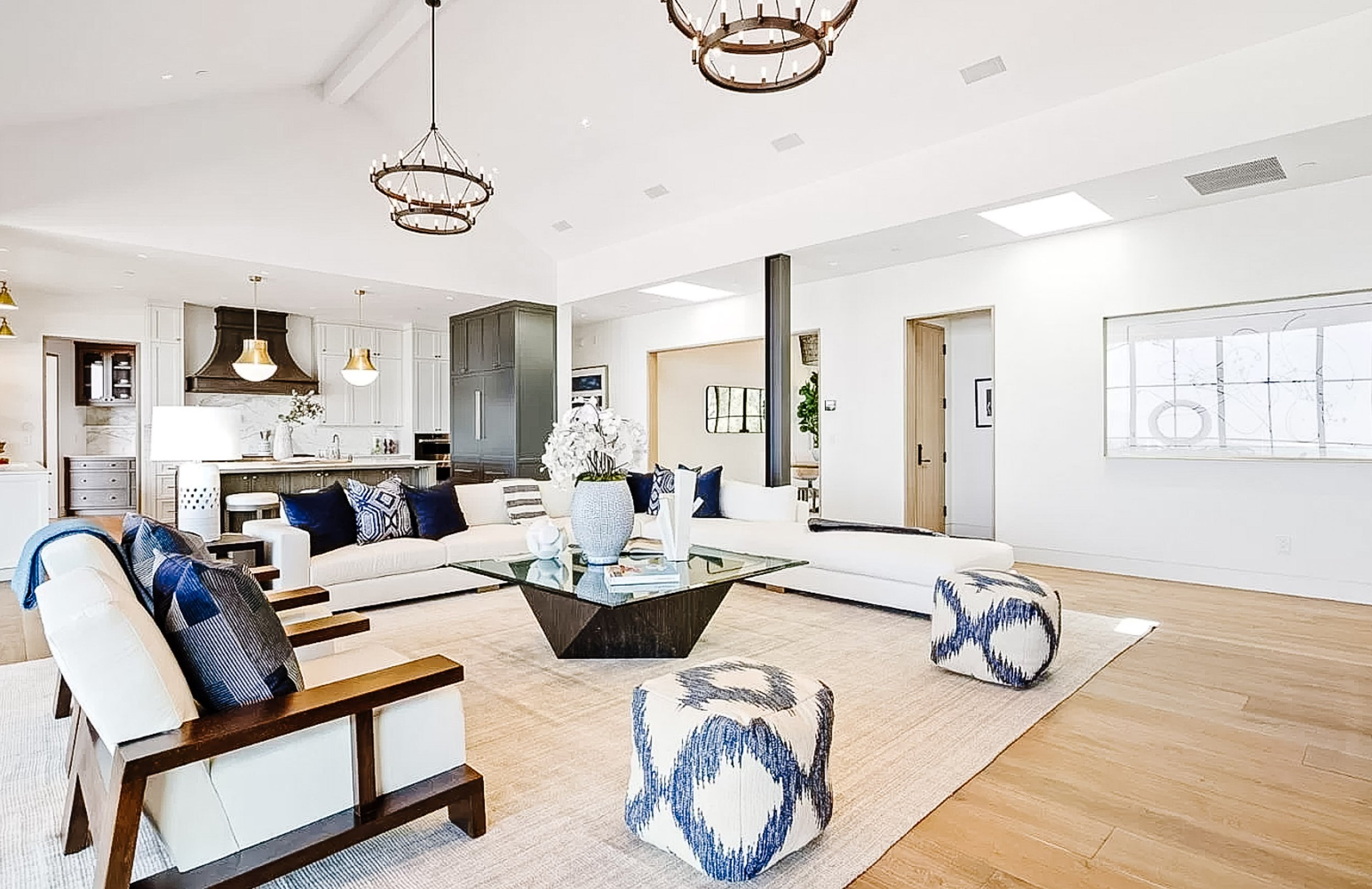 Family room, fully open to the kitchen beneath a cathedral ceiling with halo-style chandeliers, has a wall of disappearing sliding glass doors to a covered, heated terrace with amazing views; a gas-log fireplace is surrounded in sleek steel