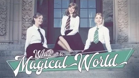 Three young women in school uniforms sitting on a stone ledge in front of a building with large windows, smiling at the camera. The text reads 'What a Magical World'.