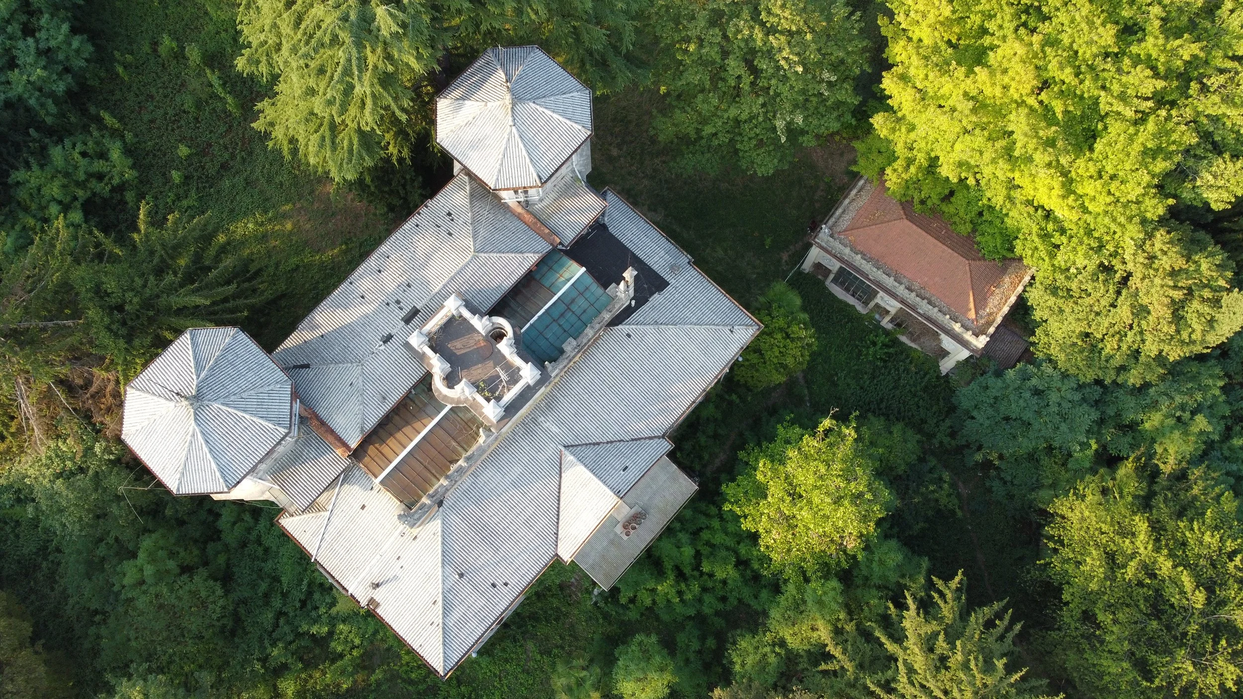 An abandoned villa and its winter garden, embedded in a forest show from above using the drone