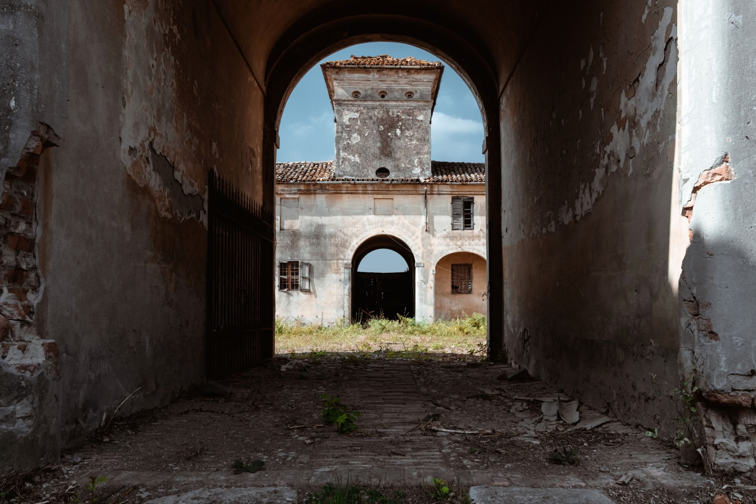 A dark archway framing a ruined tower in the light beyond