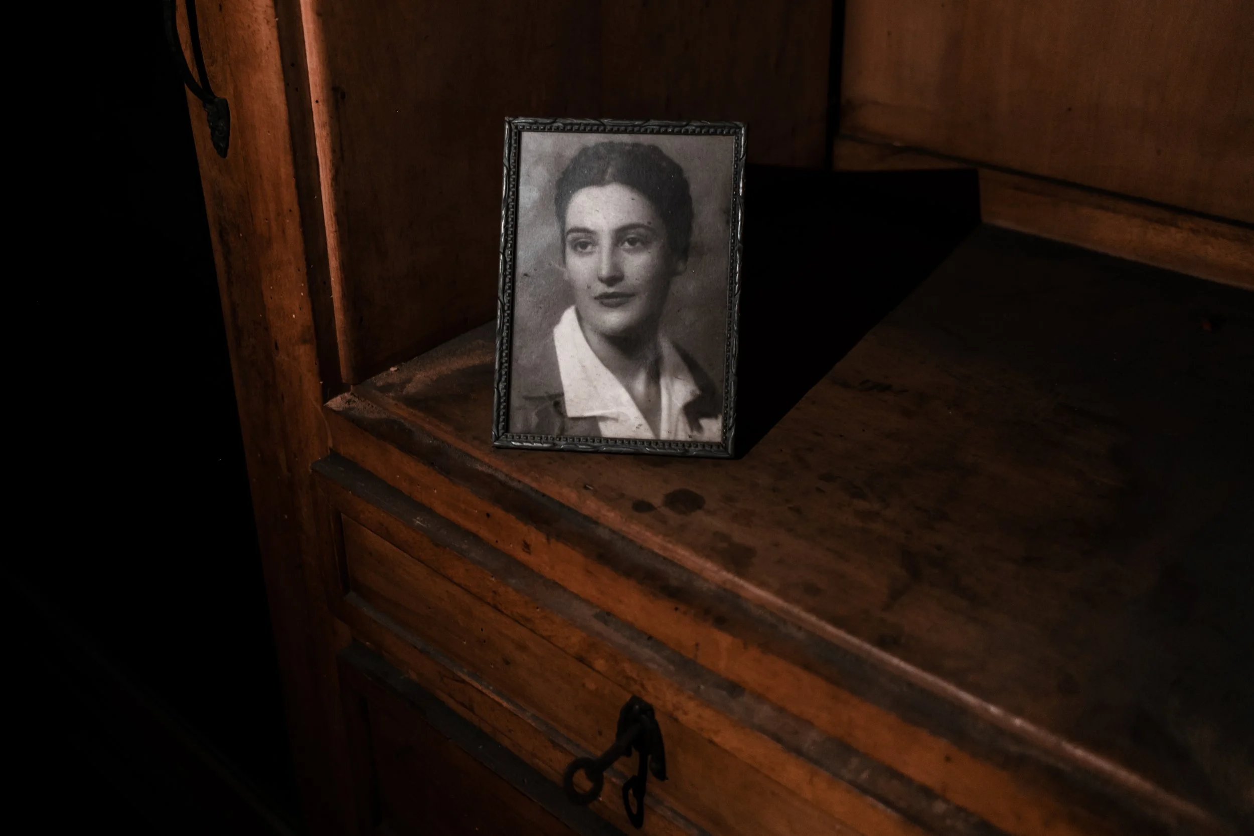 An old portrait photograph left on a dusty wooden cabinet