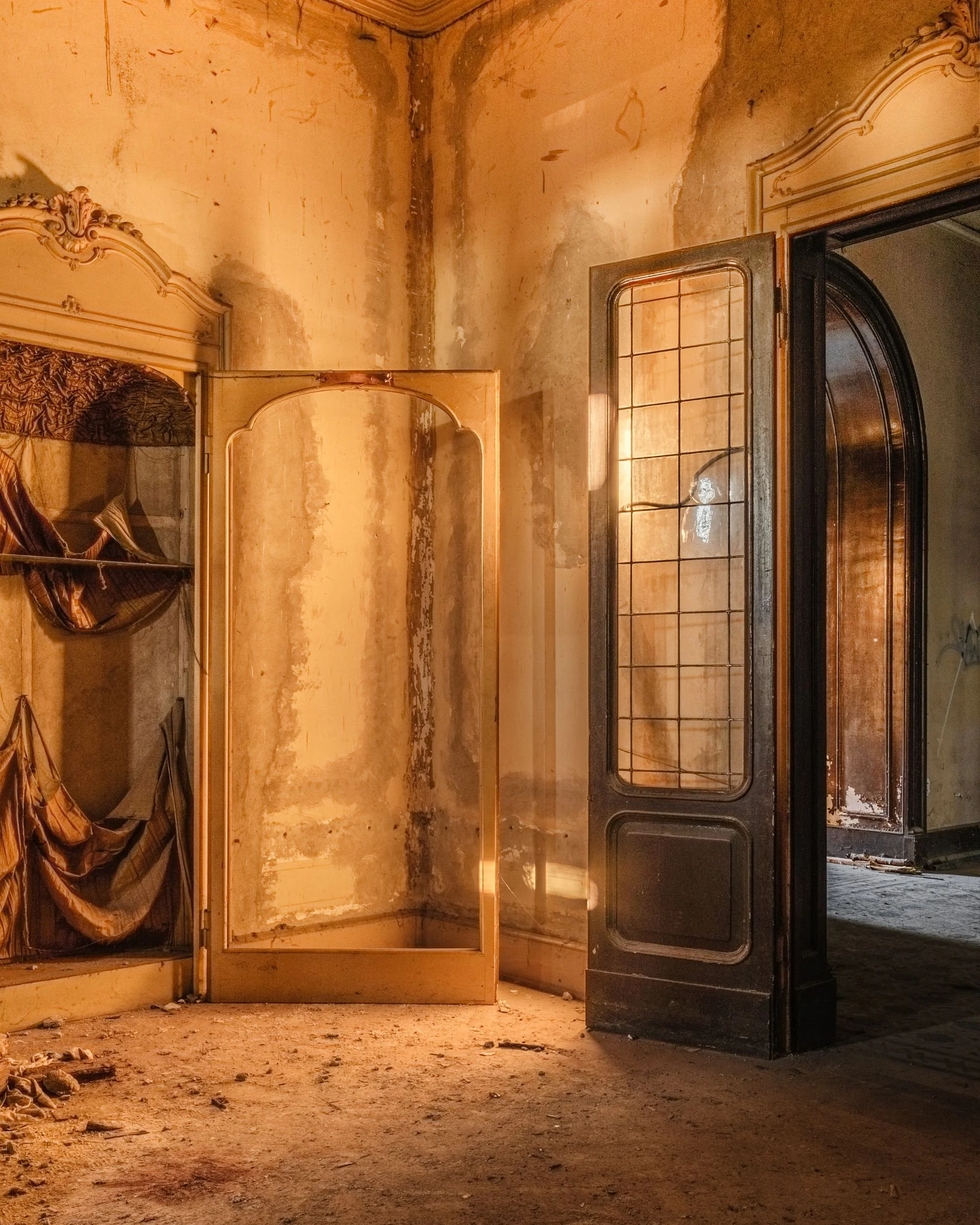 Open doors in a room washed in warm light, paint peeling from the walls