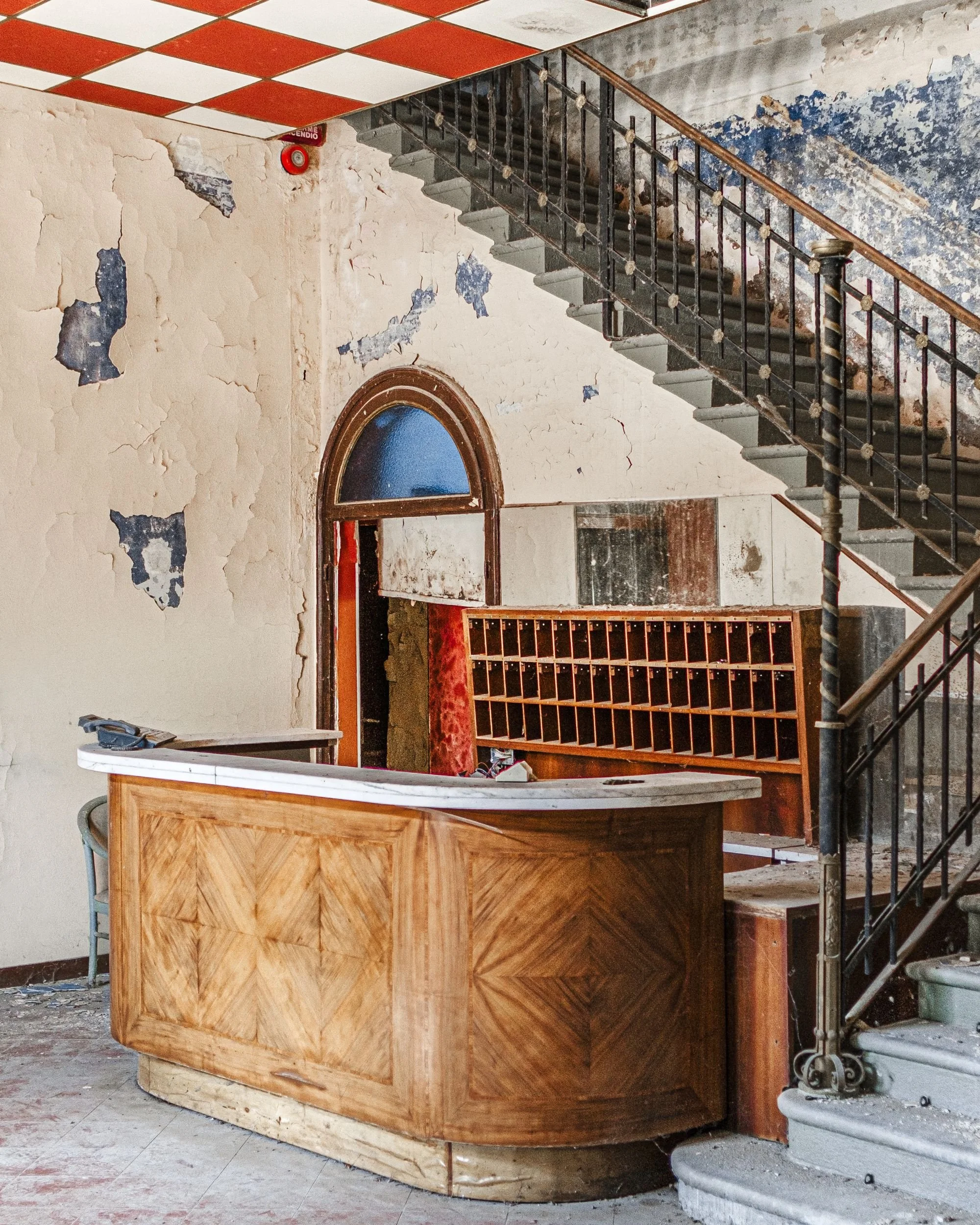 A carved wooden reception desk abandoned at the foot of a staircase