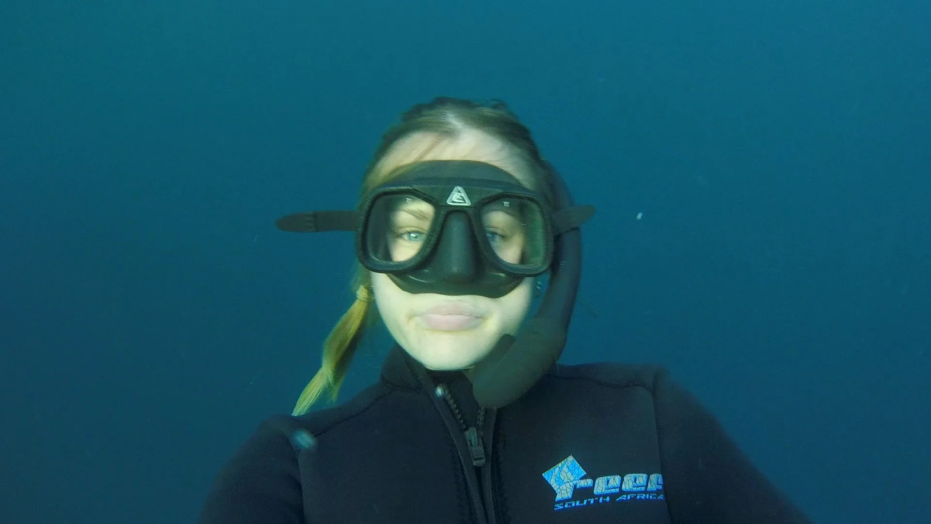Snorkel guide Keira Lintin underwater wearing a mask and snorkel, looking directly at the camera.