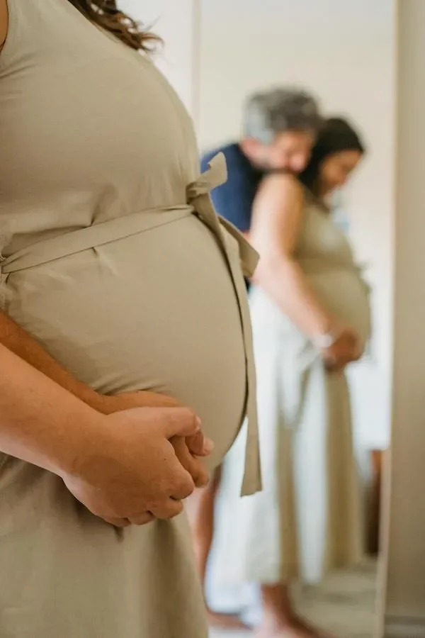 A pregnant couple looking in a mirror