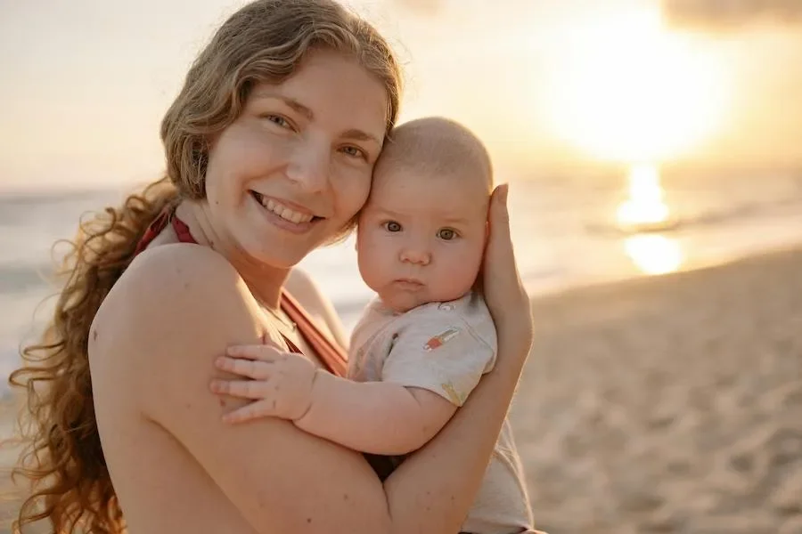 A smiling mom and newborn on the beach