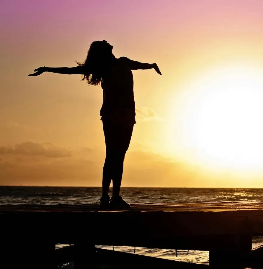A person standing by the sea with open arms