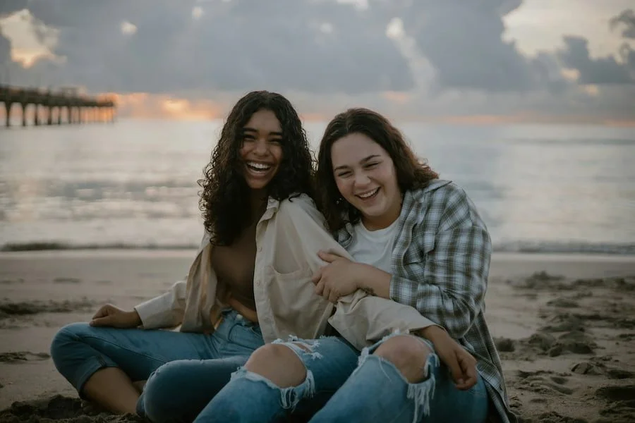 Two teen girls on the beach laughing