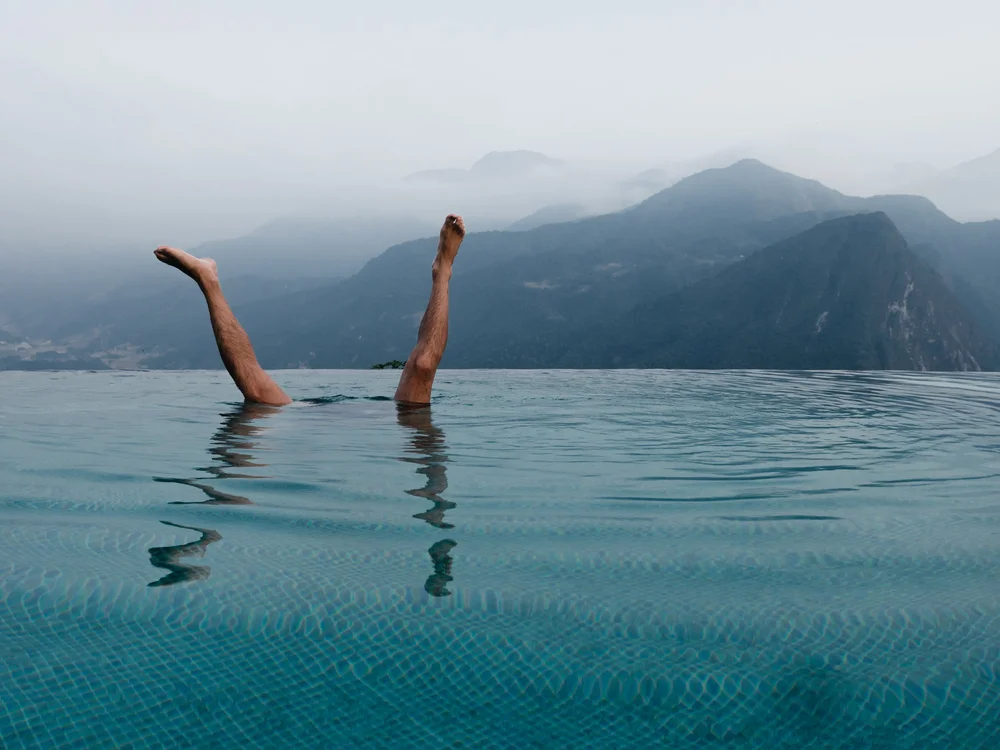 Tim doing a handstand in an infinity pool in front of the mountains