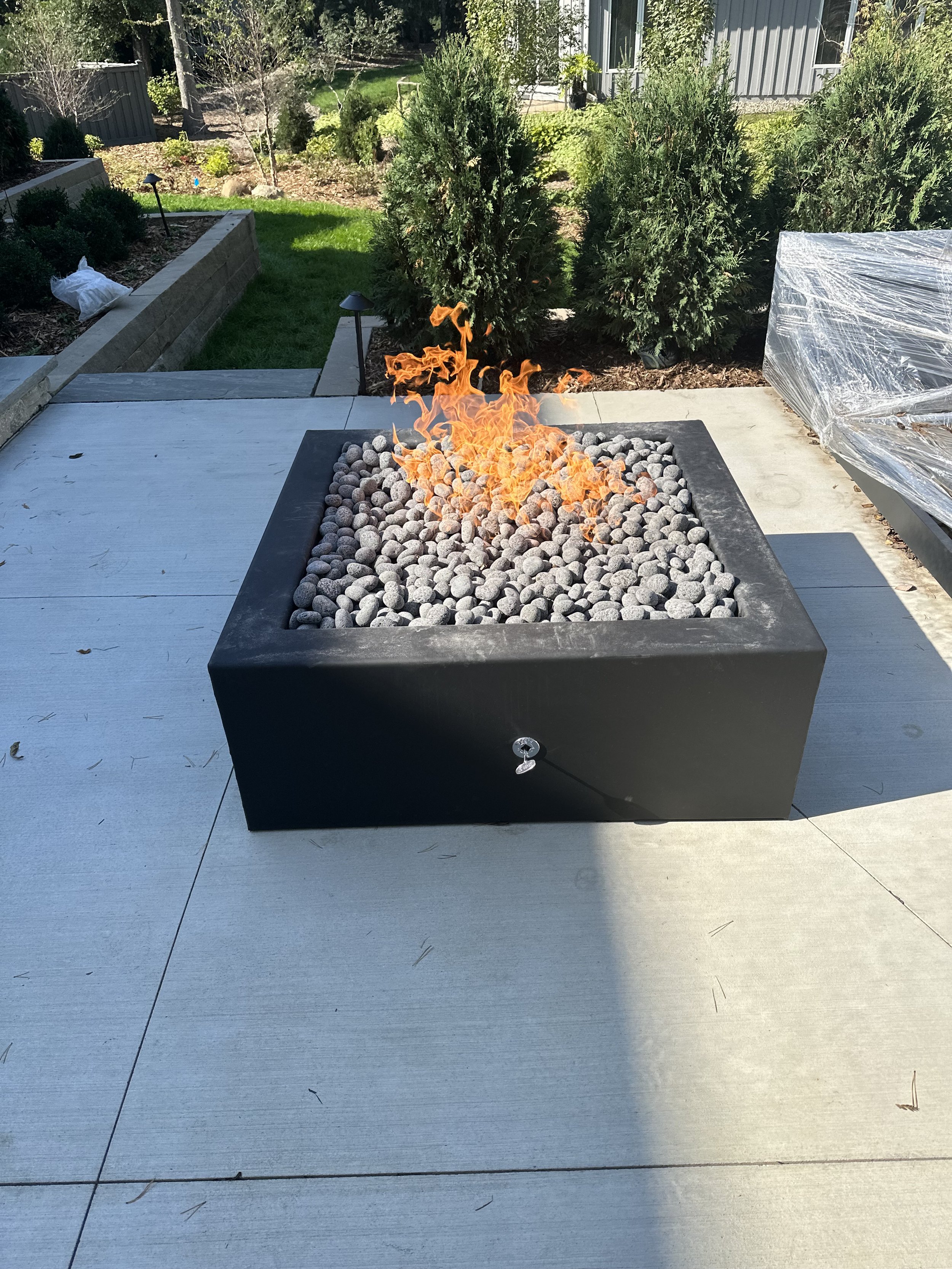 Black fire pit with grey rolled stone media.jpeg