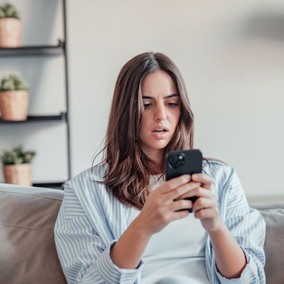A woman looking upset at her phone