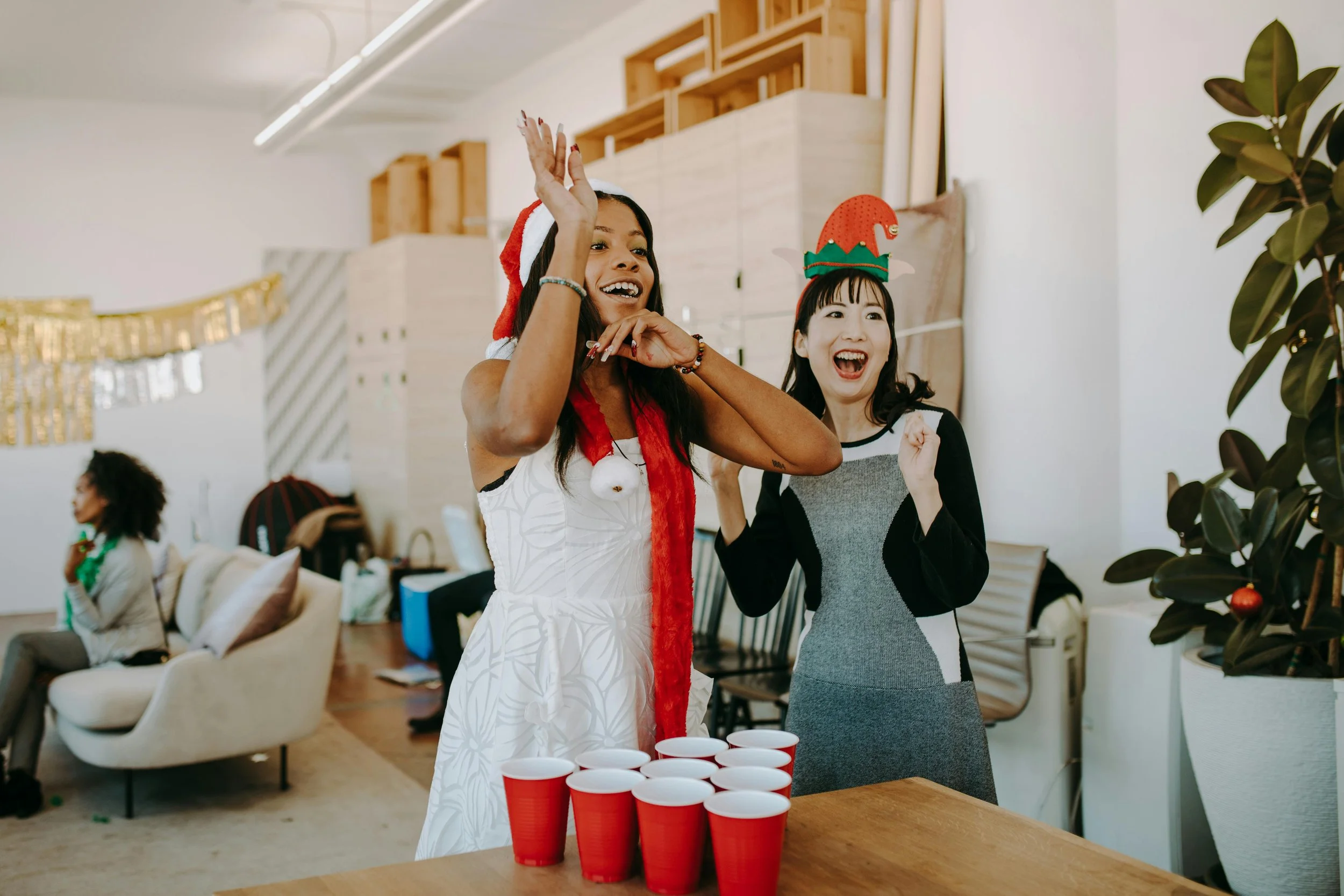 Two friends at a Christmas party playing beer pong