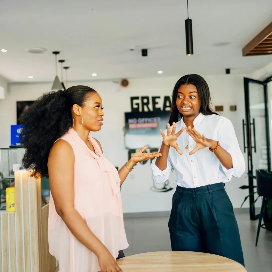 Two friends having a conversation, looking uncomfortable