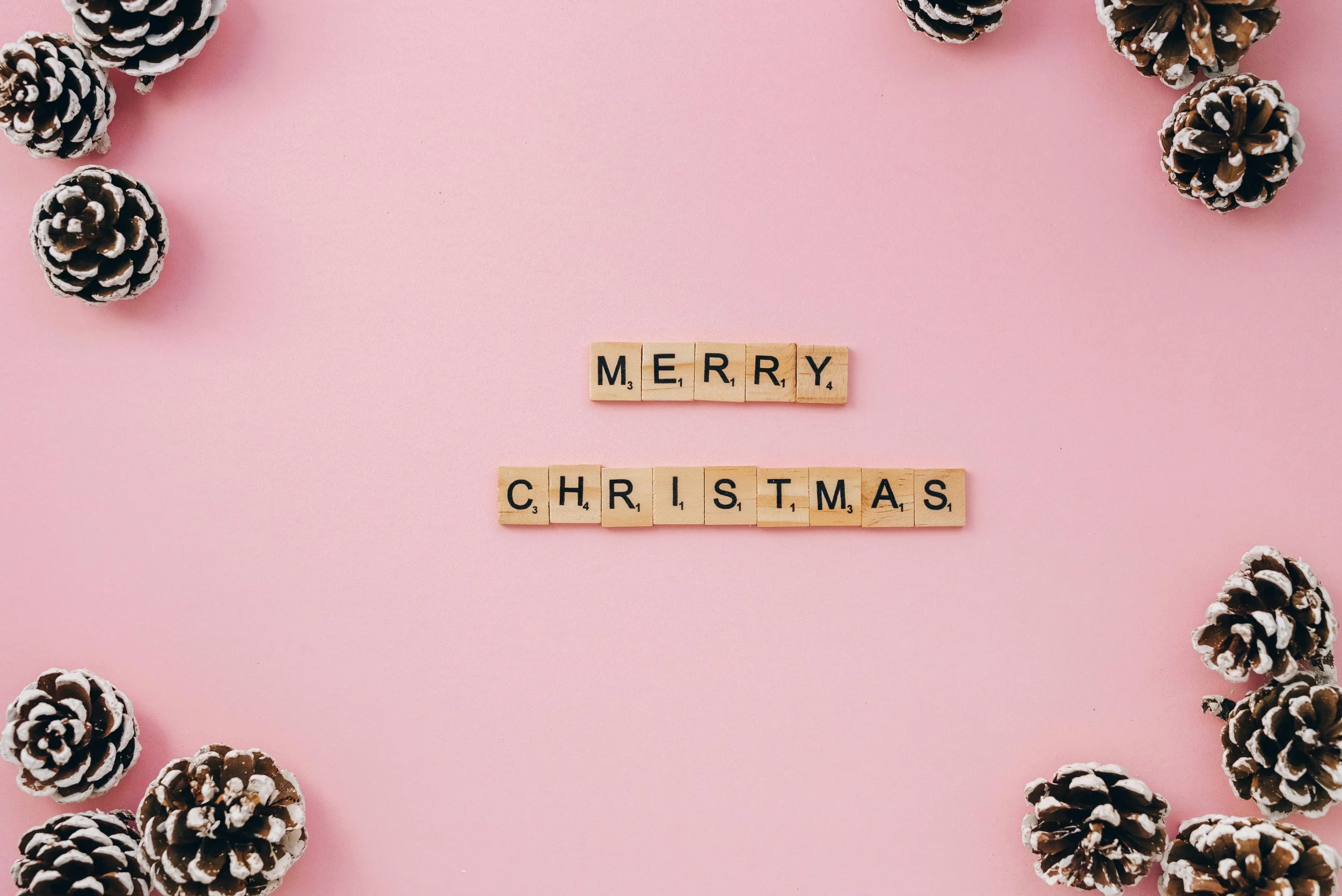 Pink background with a scrabble Merry Christmas sign