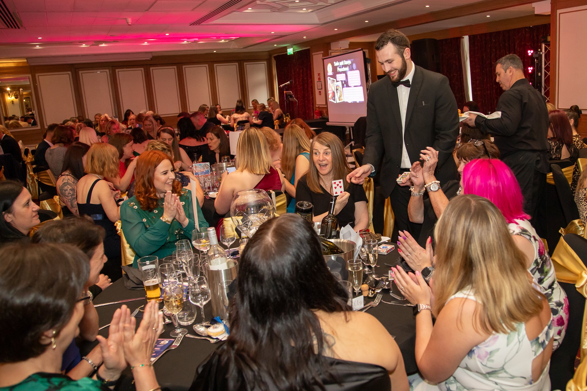 corporate magician is performing magic between courses at a sit down corporate meal