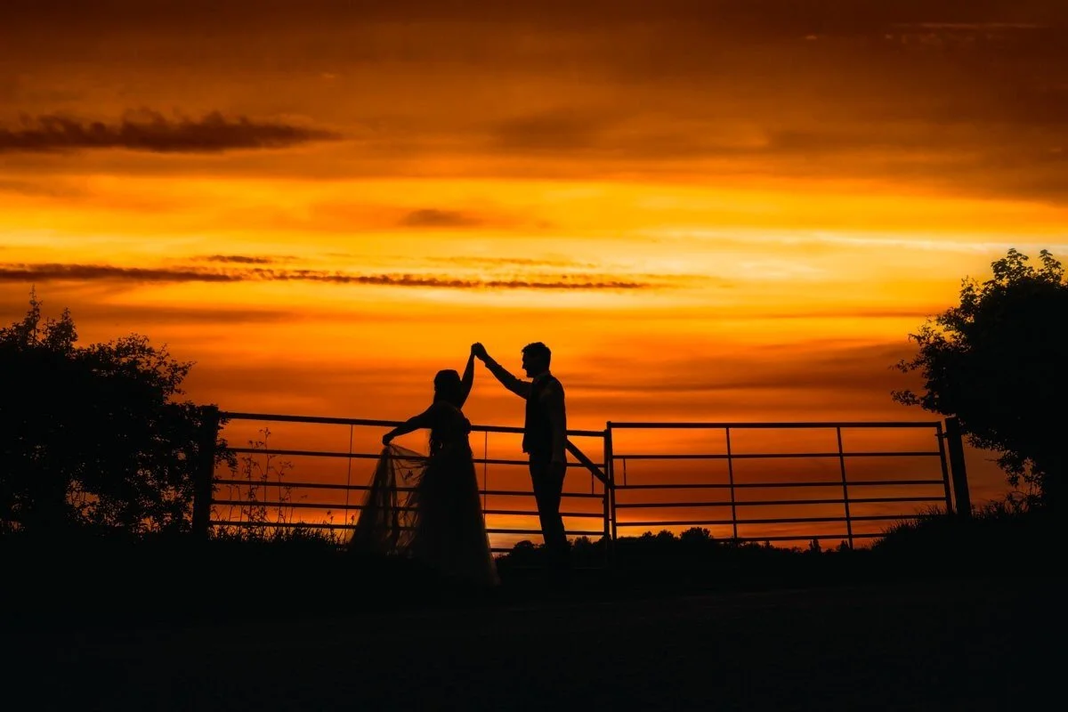 the wedding couple are photographed in front of the sunset.