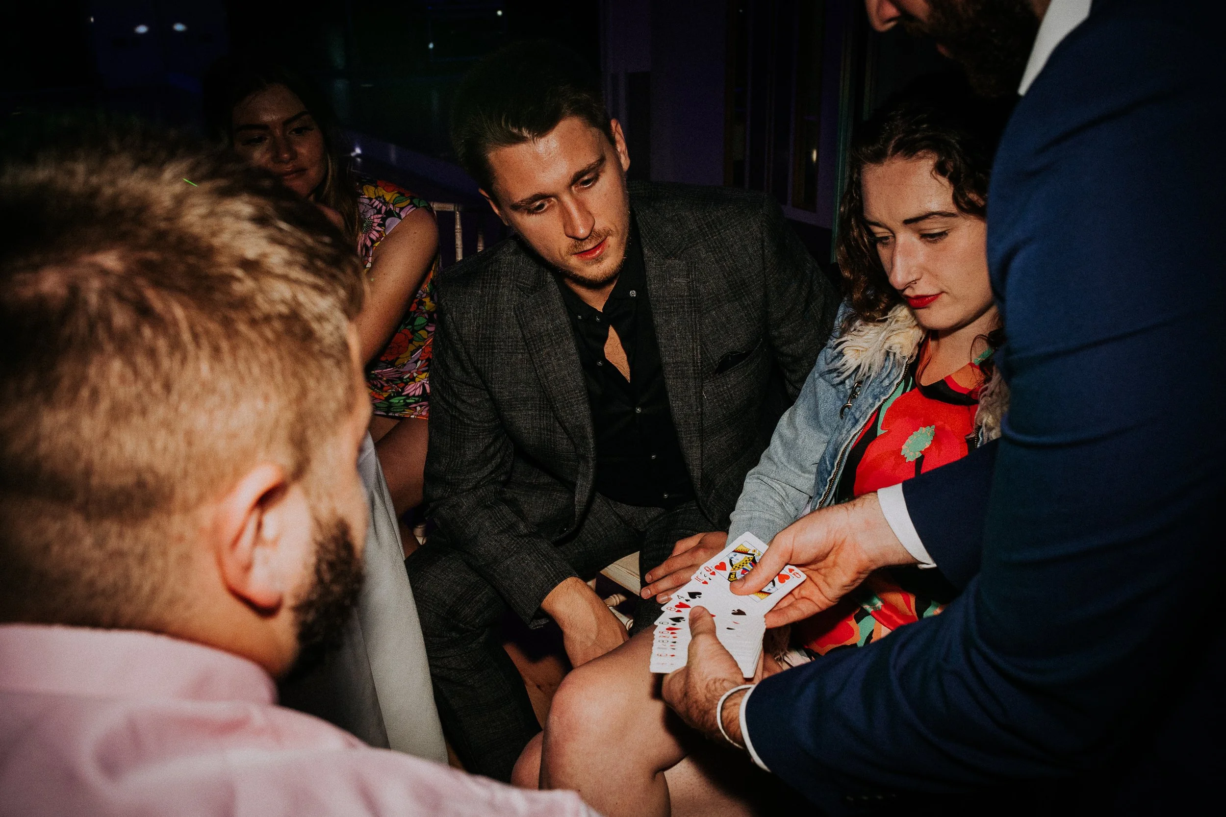 magician Revilo Twist is doing a card trick for a group of guests at a private party
