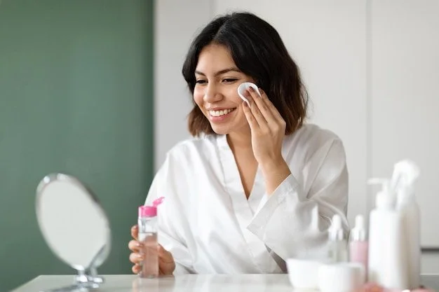 Woman in white shirt applying skincare on her face in a bathroom or vanity area.