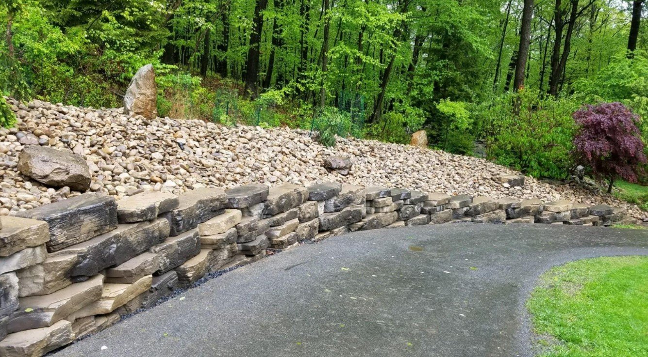 stone retaining wall with smaller rocks going down the drive way