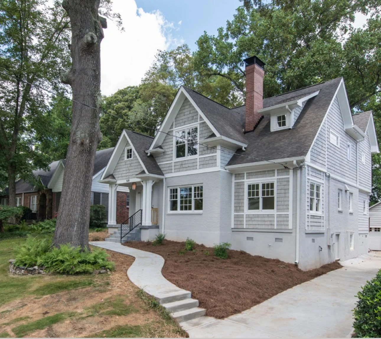Renovated Craftsman-style home with light gray siding, white trim, dark asphalt roof, and seamless white gutters