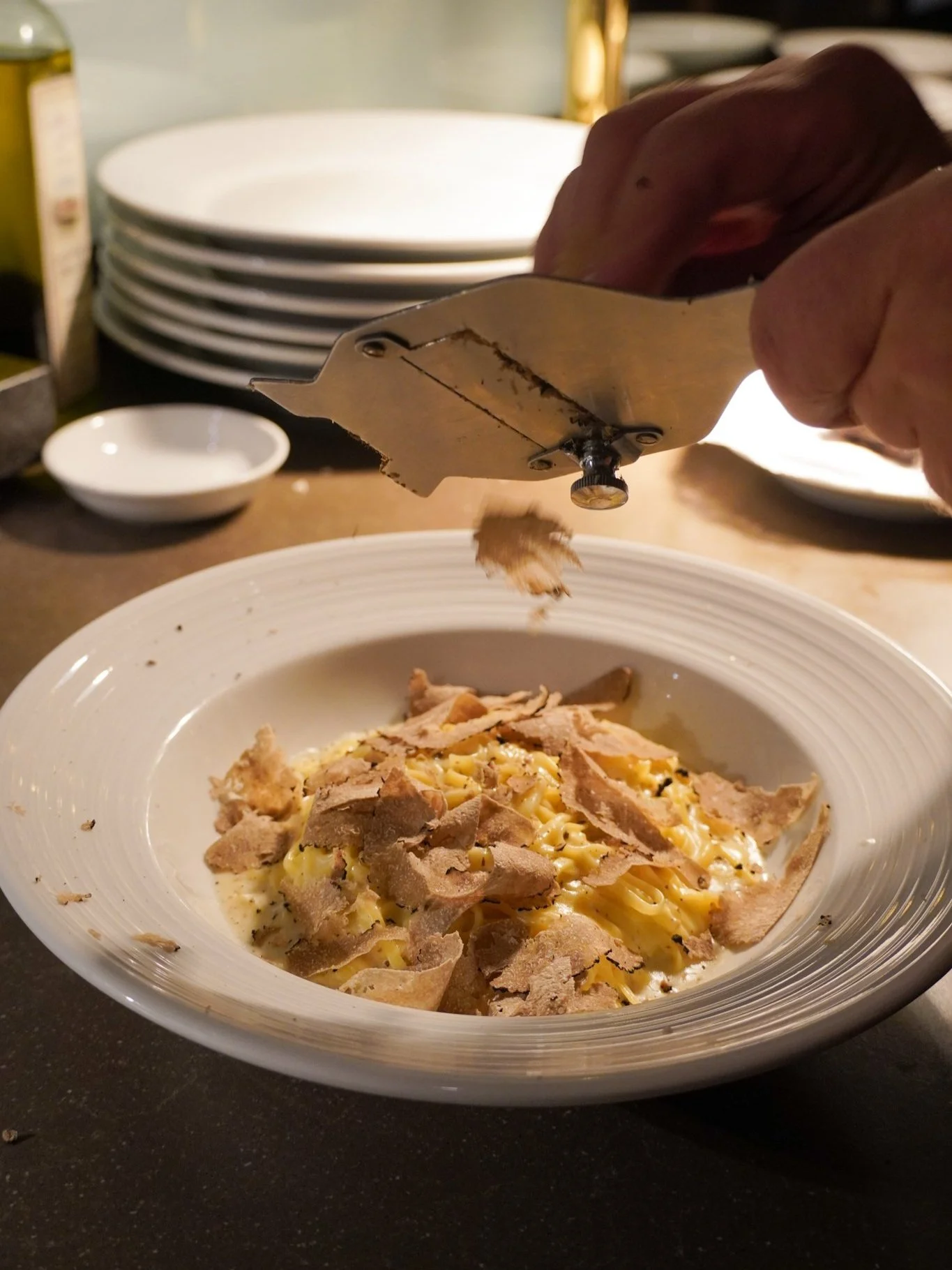 Photo of plated menu item Tagliatelline al Tartufo with staff slicing fresh mushrooms on top.