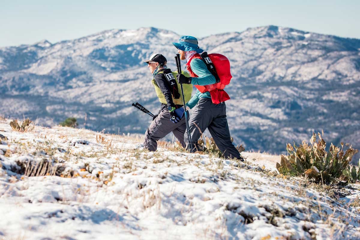  Two runners hike through snowy conditions and blue skies at Tahoe 200 
