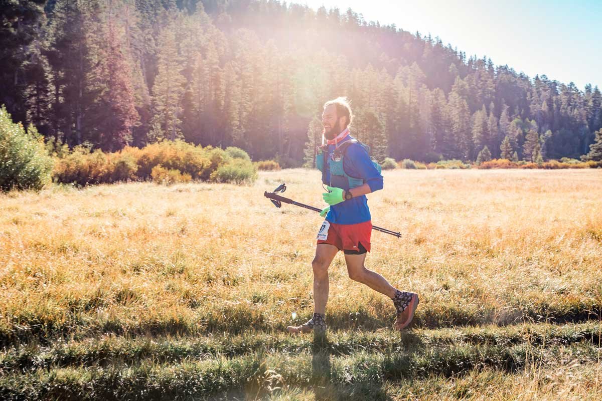  A lone male runner moving through a golden meadow at Tahoe 200 