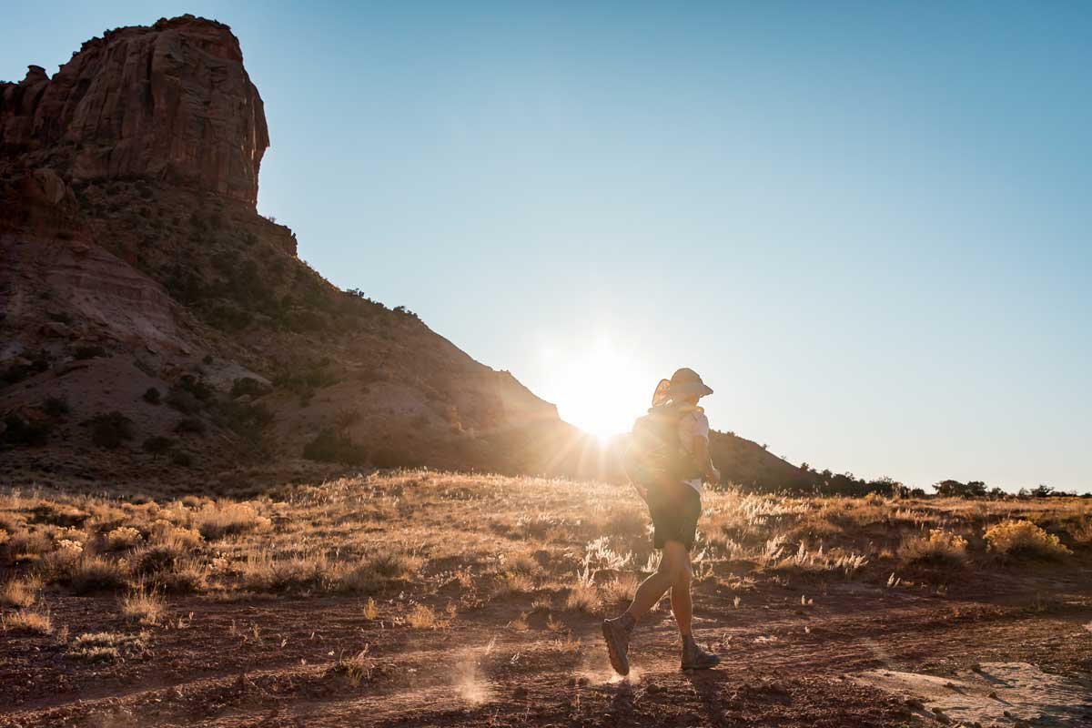  Desert sunset over a mesa as a runner traverses the sandy trails 