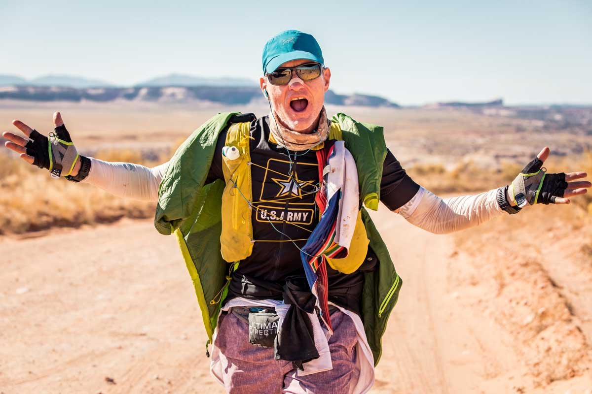  Runner singing in the desert wearing a running pack and ultra running gear  