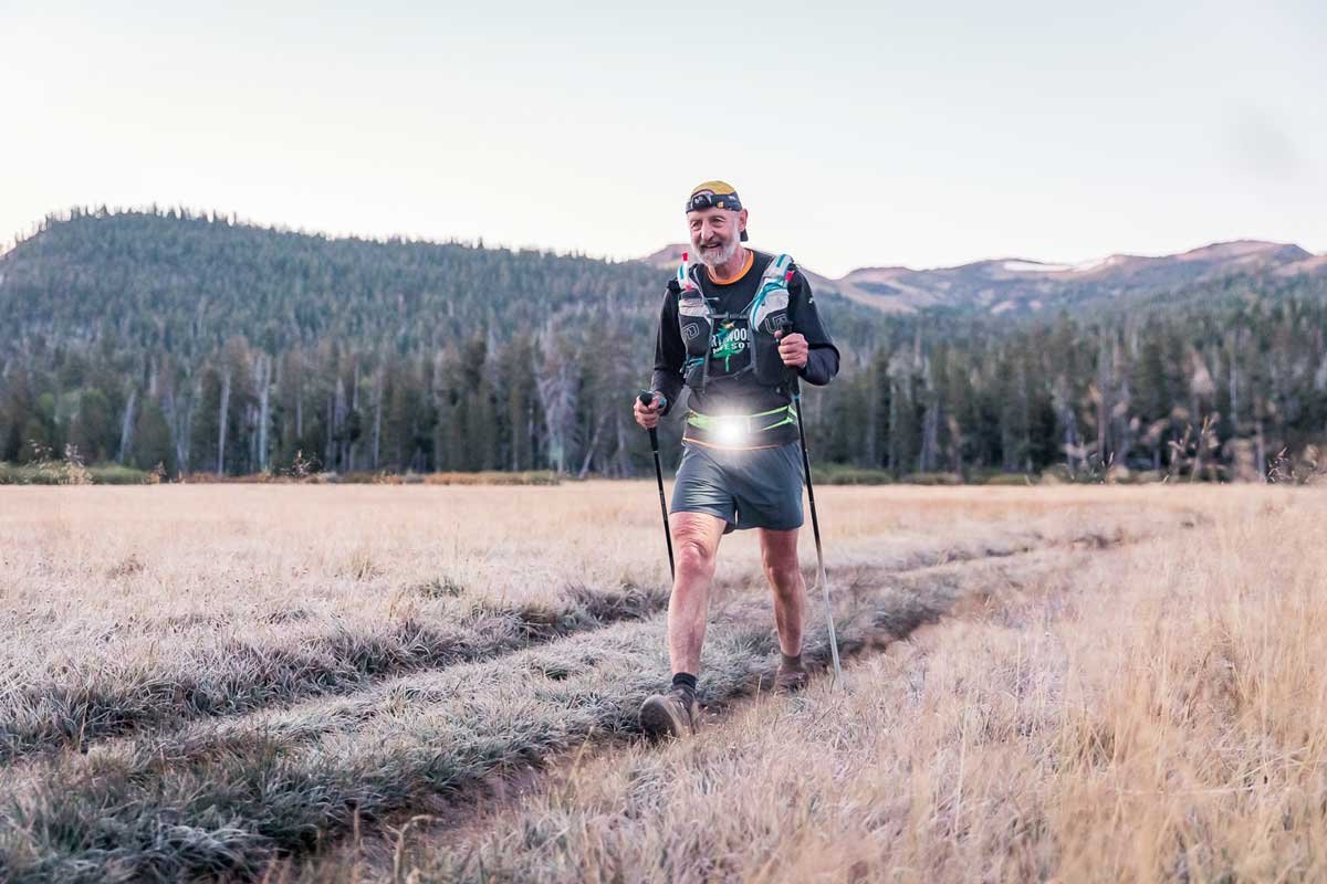  A runner with his waist headlamp on, makes his way through a cold meadow at dawn 