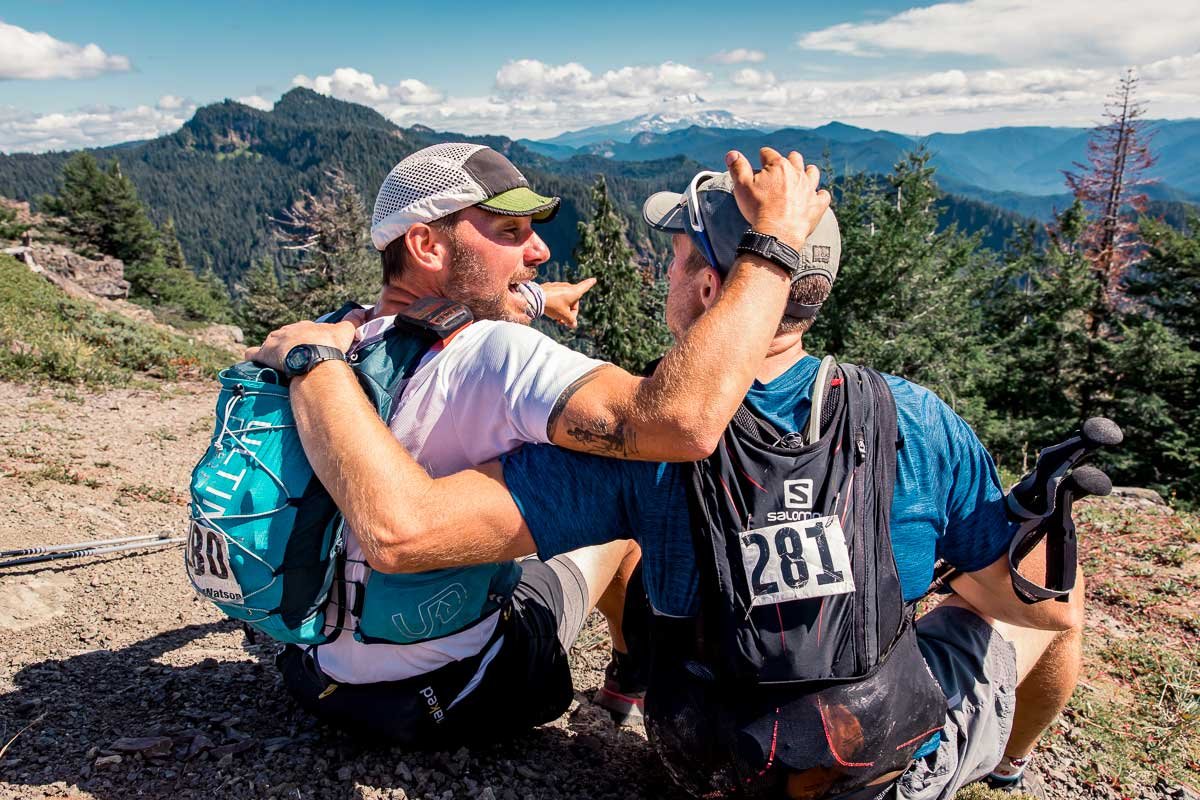  Two runners embracing and looking towards a view of the mountains together 