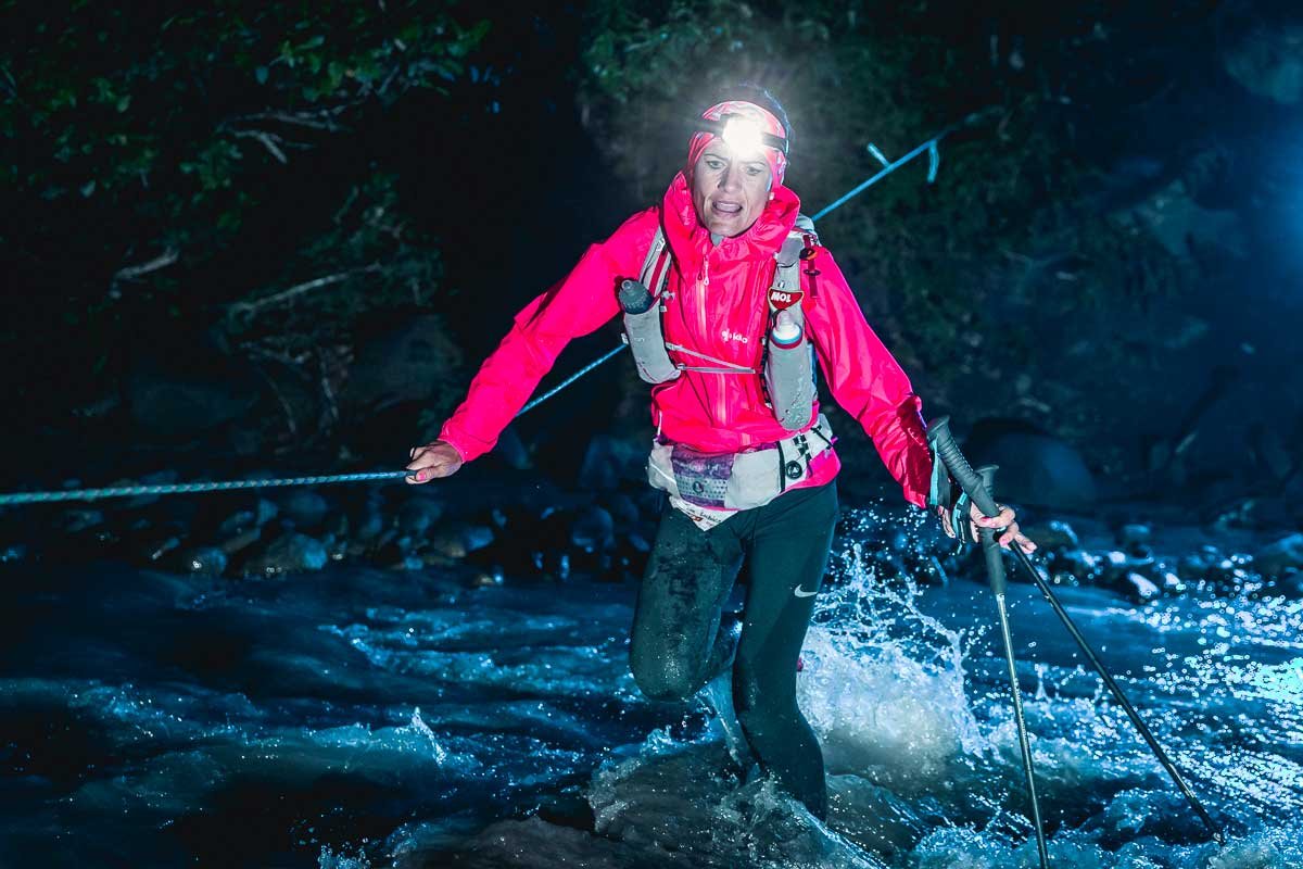  Female runner crossing a knee deep river at night by headlamp 