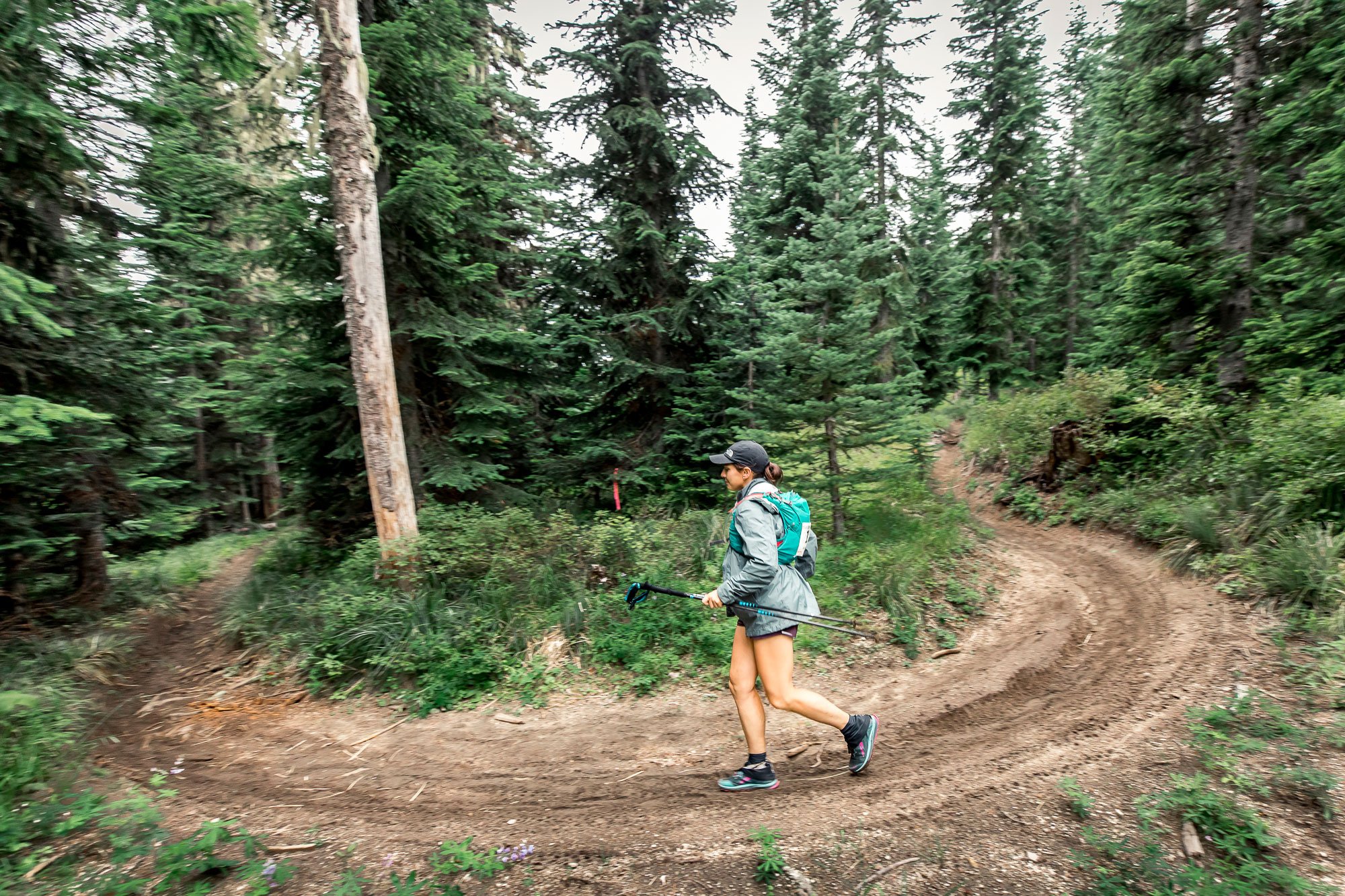  A female runner running around a horseshoe bend in the trail in the forest 