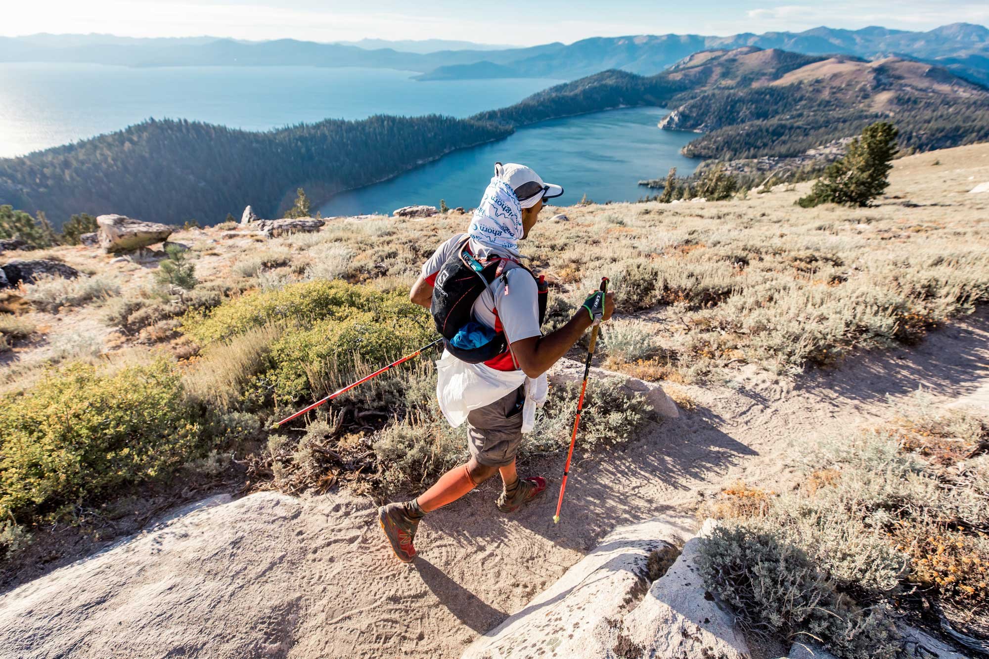  A runner passing by on a trail with Snow Valley and Lake Tahoe in the background 