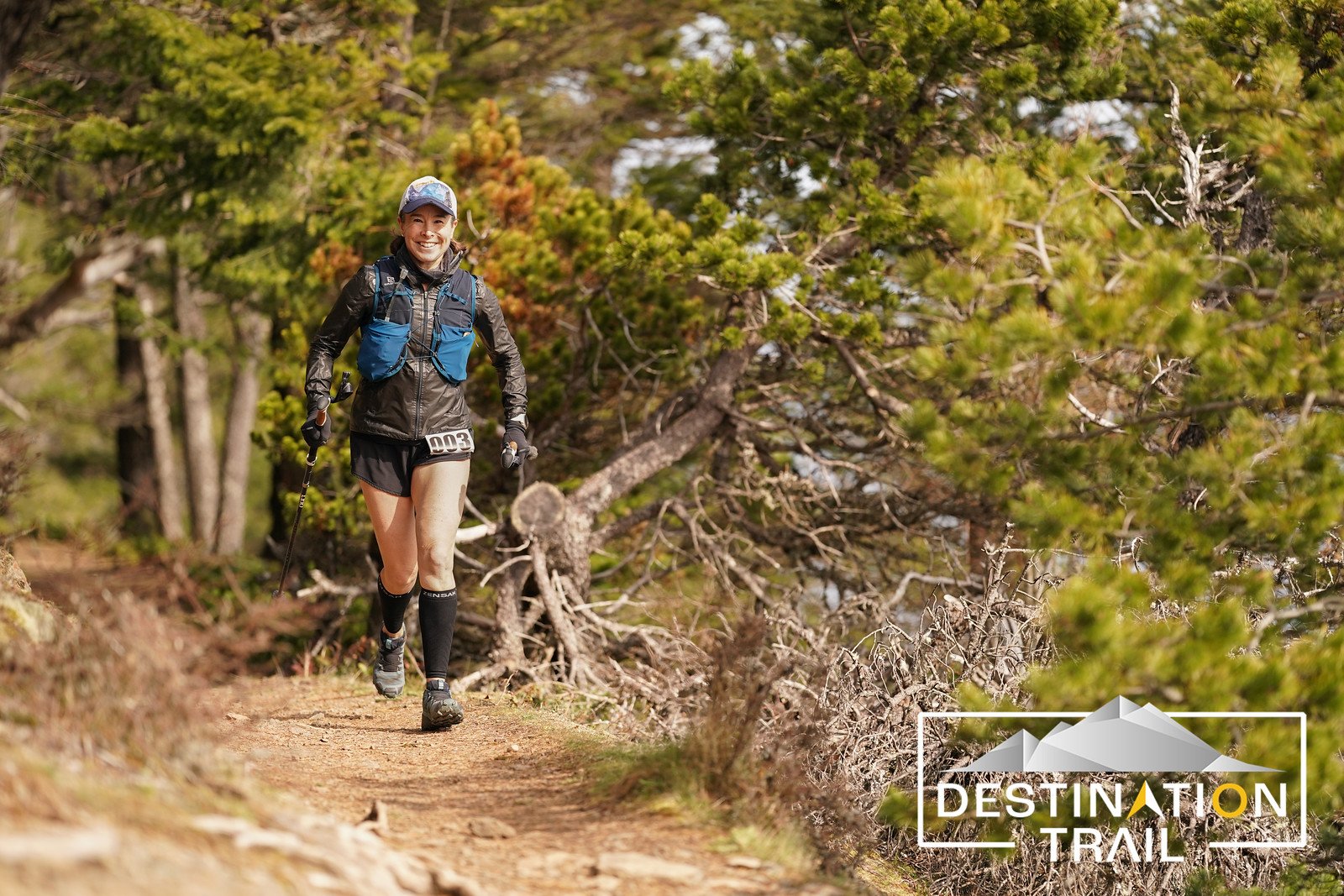  A female runner with poles running on a dirt trail 