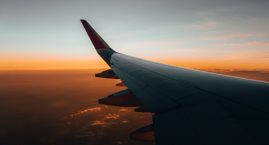 Airplane wing at sunset above the clouds.