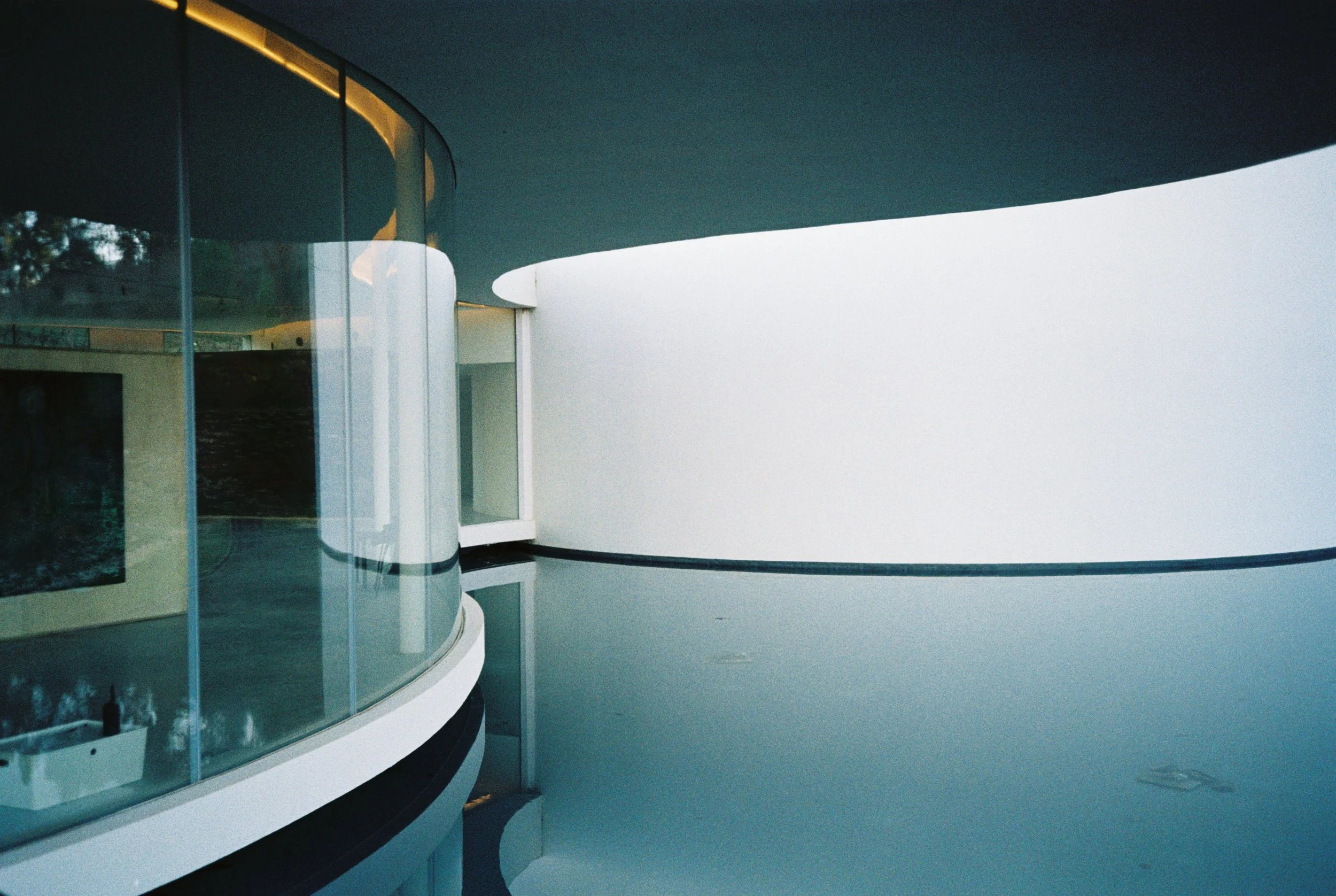 Modern architectural building with curved lines and large glass windows, set against a clear sky.