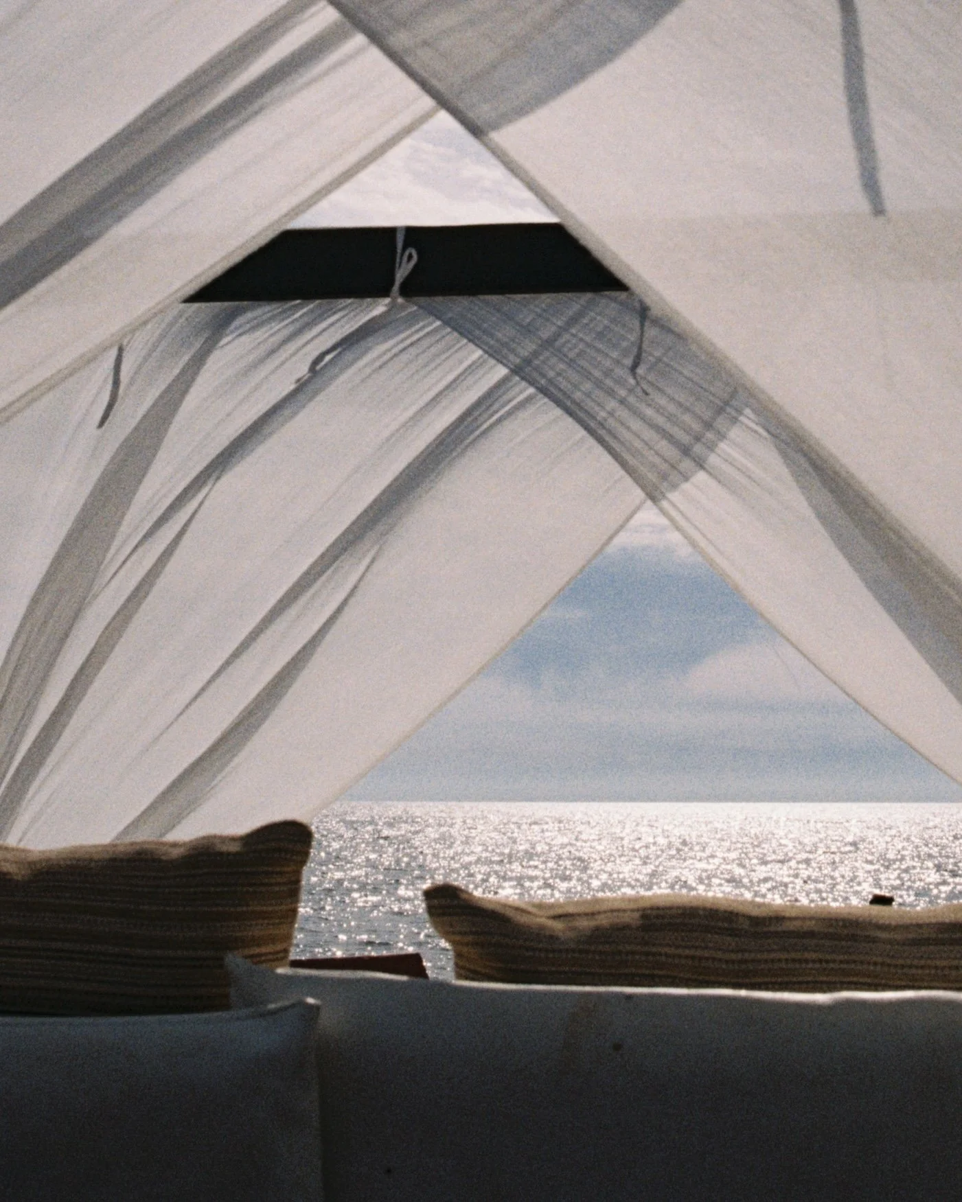 View from inside a boat looking out through an opening at the ocean and sky, with sunlight reflecting on the water.
