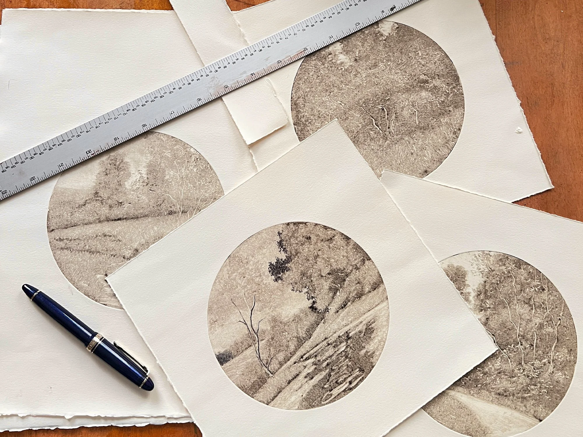 A stack of tondo landscape monotype ghost prints on a desk.
