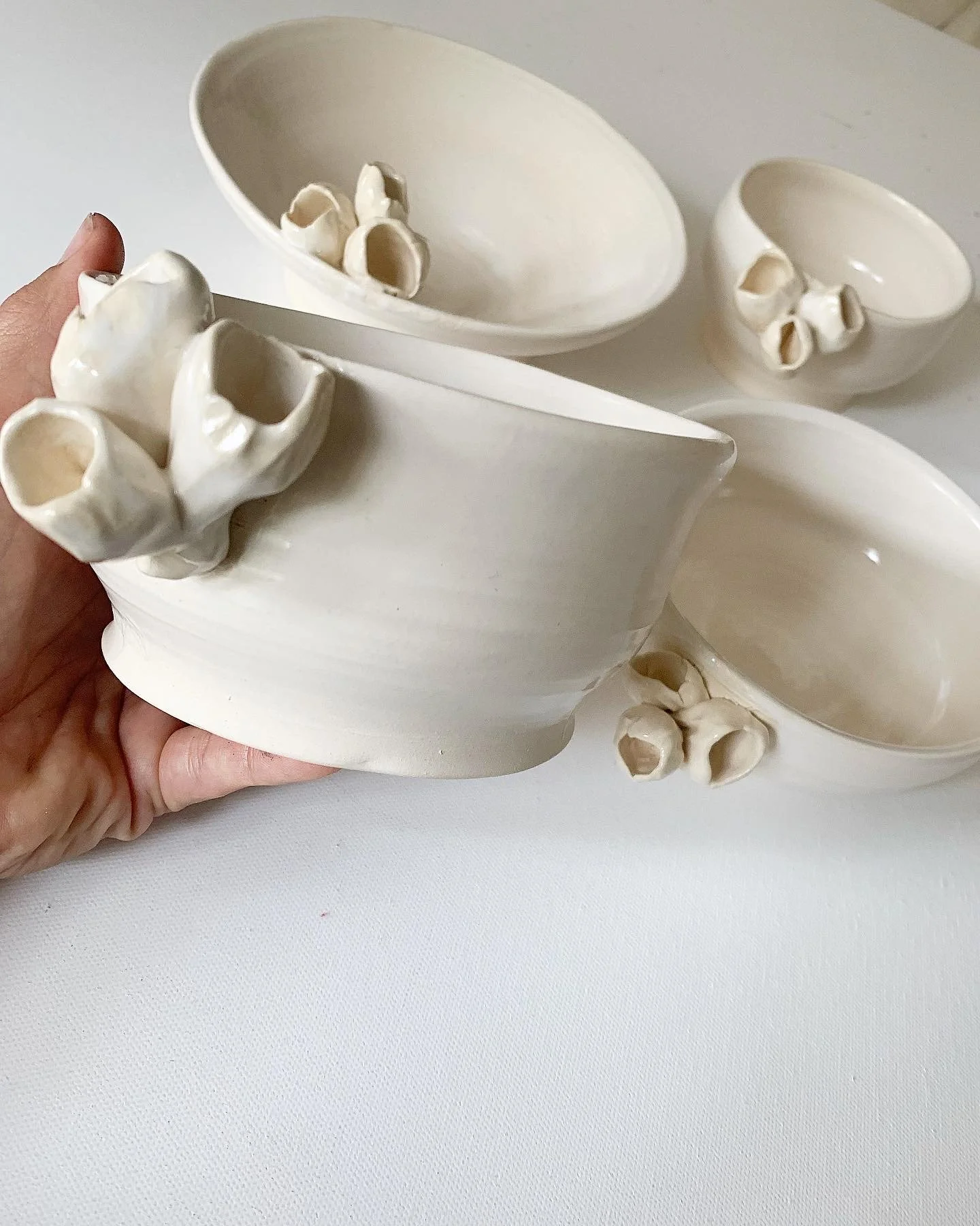 White ceramic bowls with small clay horns in a minimalist design, arranged on a white surface.