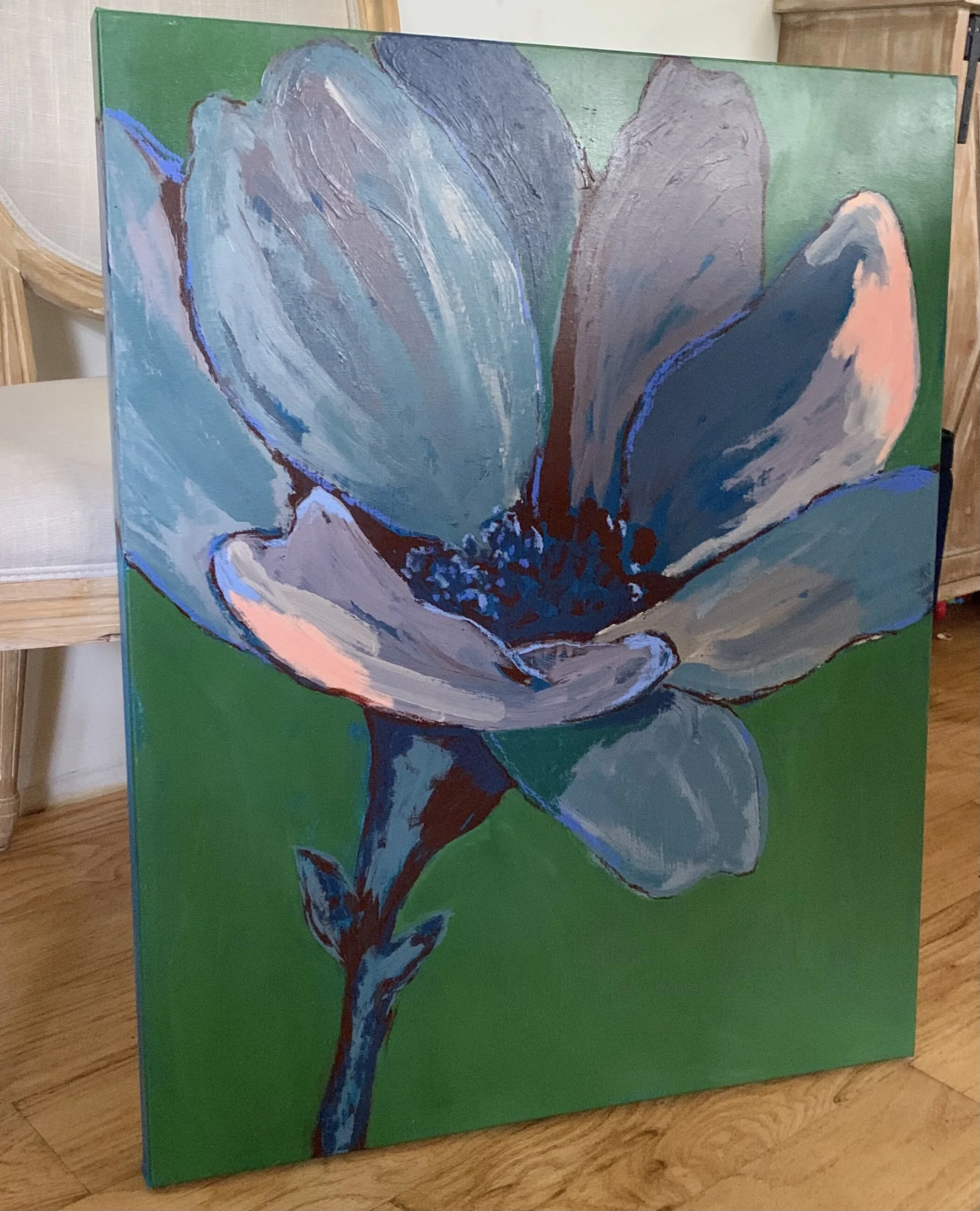 A painting of a large flower with blue, gray, and pink petals on a green background.