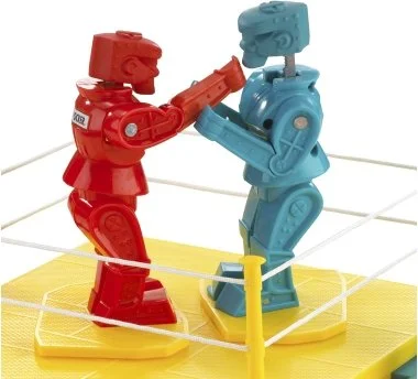 Two toy robots, one red and one blue, appear to be holding hands on a yellow platform with a web-like setup.