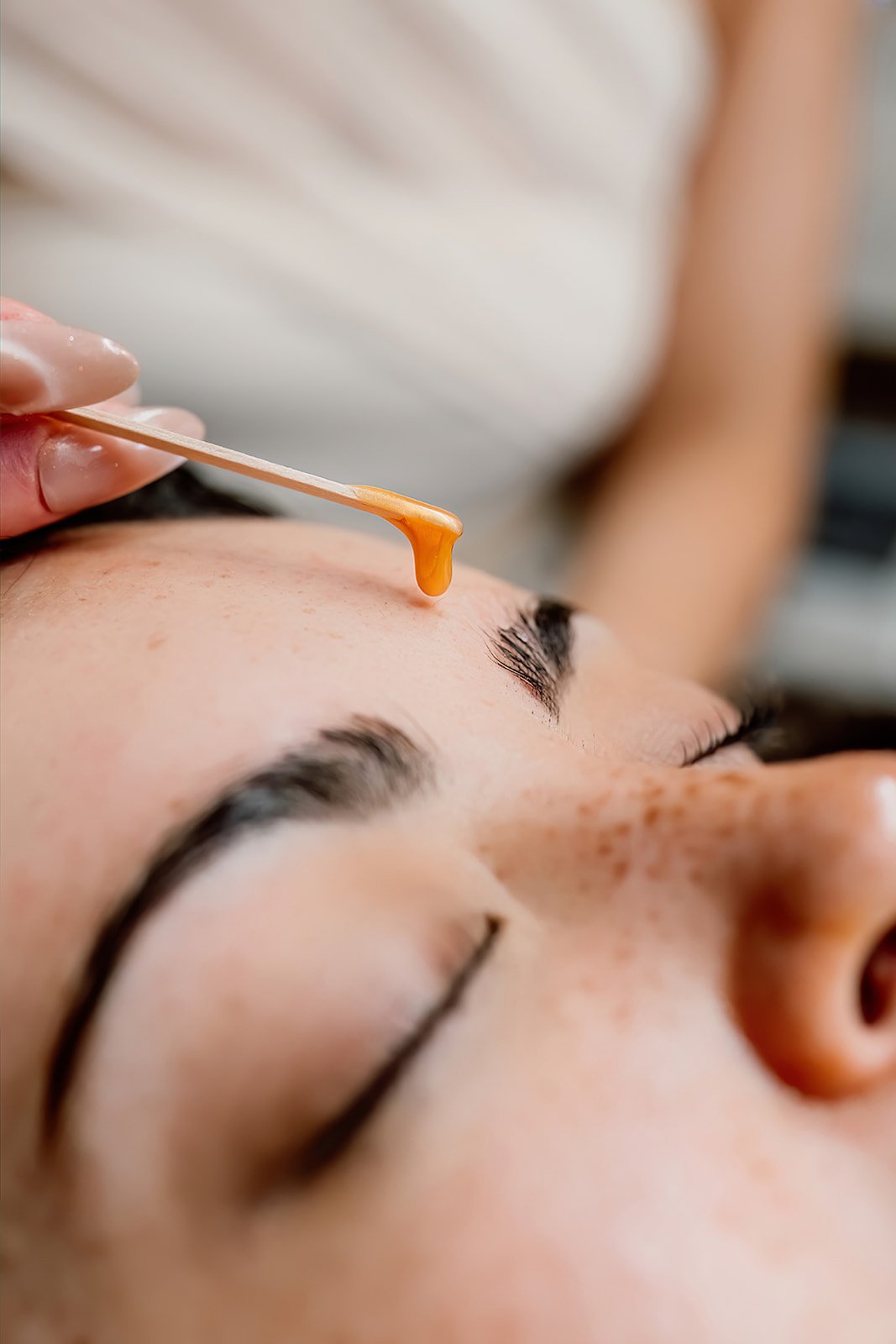 A person applying black eyeshadow to a woman's eyelid with a small brush during makeup application.