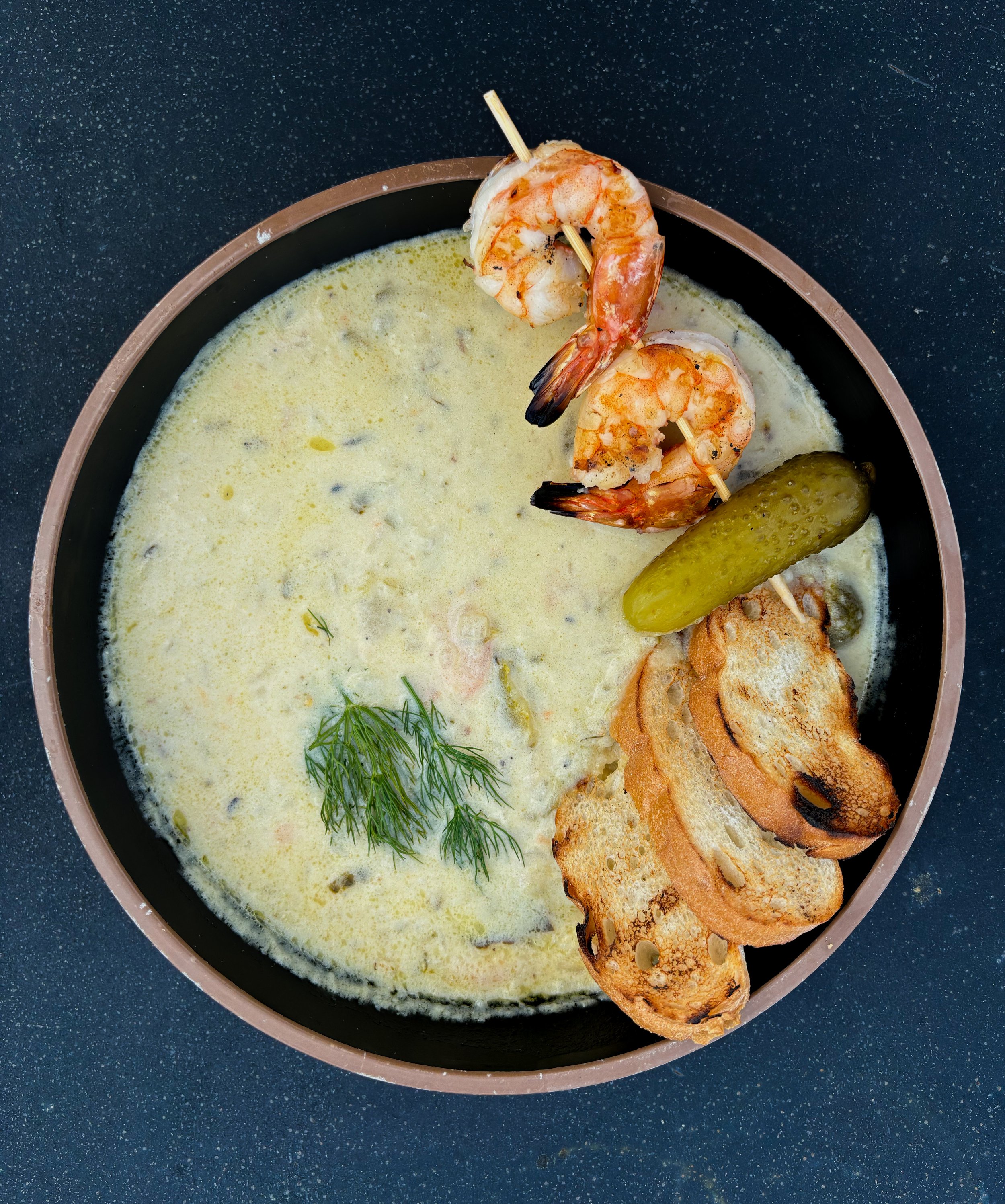 Polish Pickle Soup - Creamy, tangy soup made with fermented dill pickles, potatoes, and fresh herbs, served with grilled shrimp and bread for dipping.
