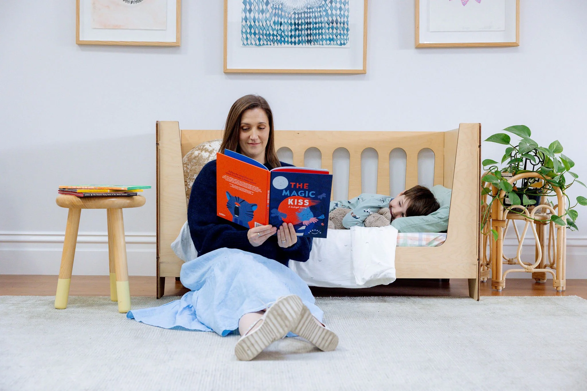 Sleep consultant Gerri Florence reading a book to a young boy laying in bed.