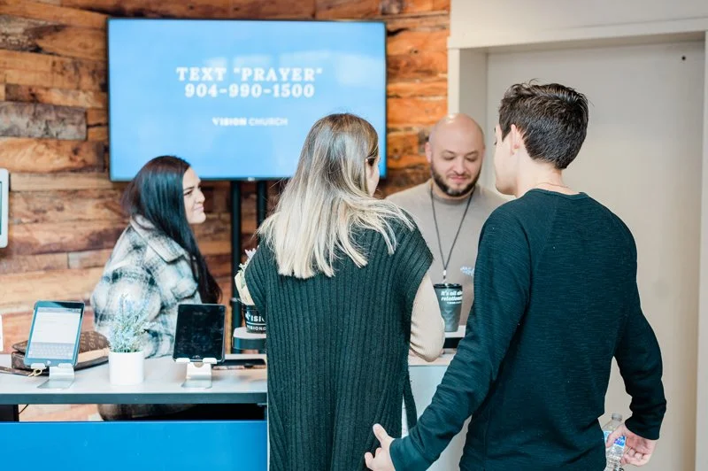 A group of people waiting in line at Vision's "Connect Corner" after service.