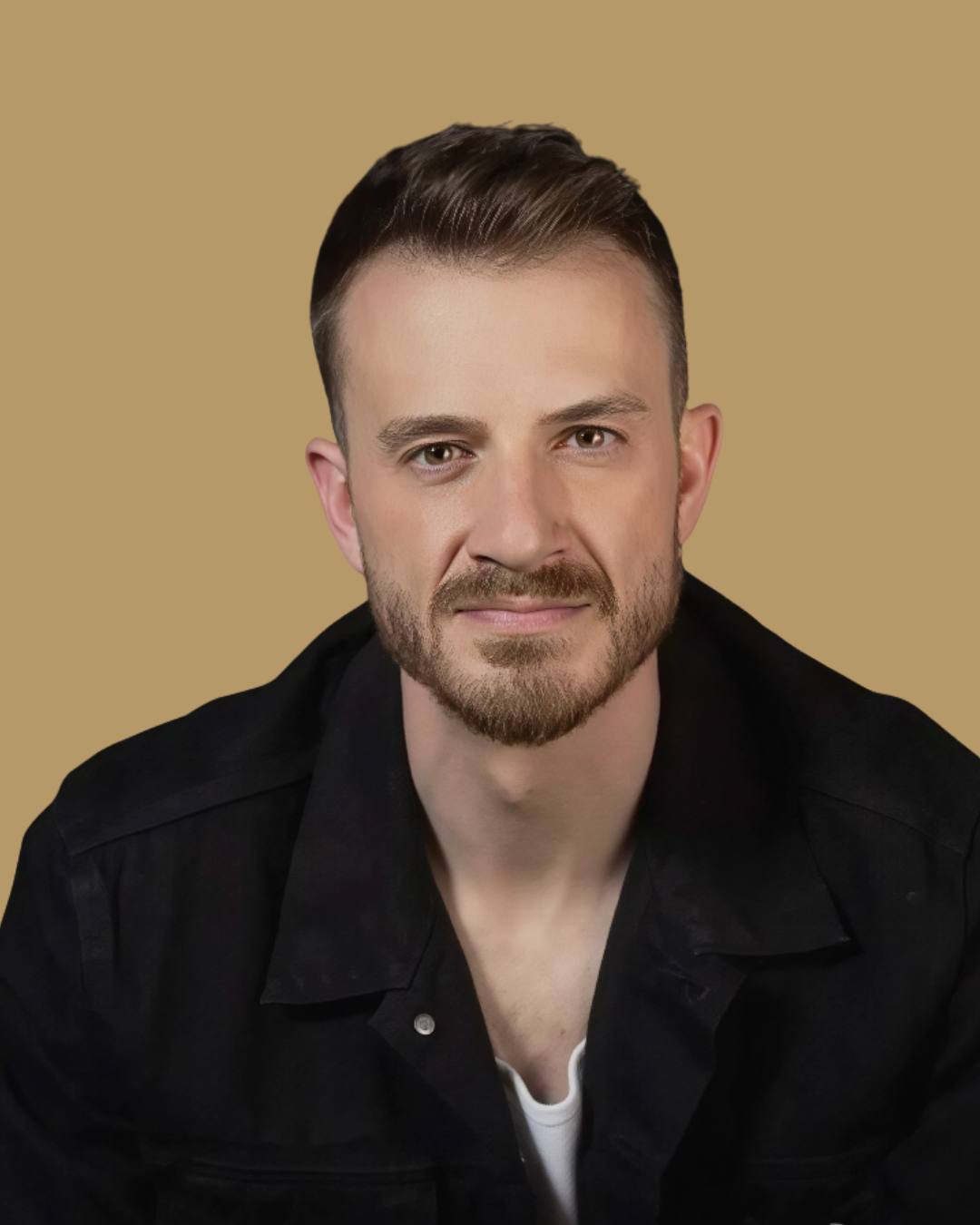 Portrait of a man with light skin, short brown hair, and a beard, wearing a black jacket over a white shirt, against a beige background.