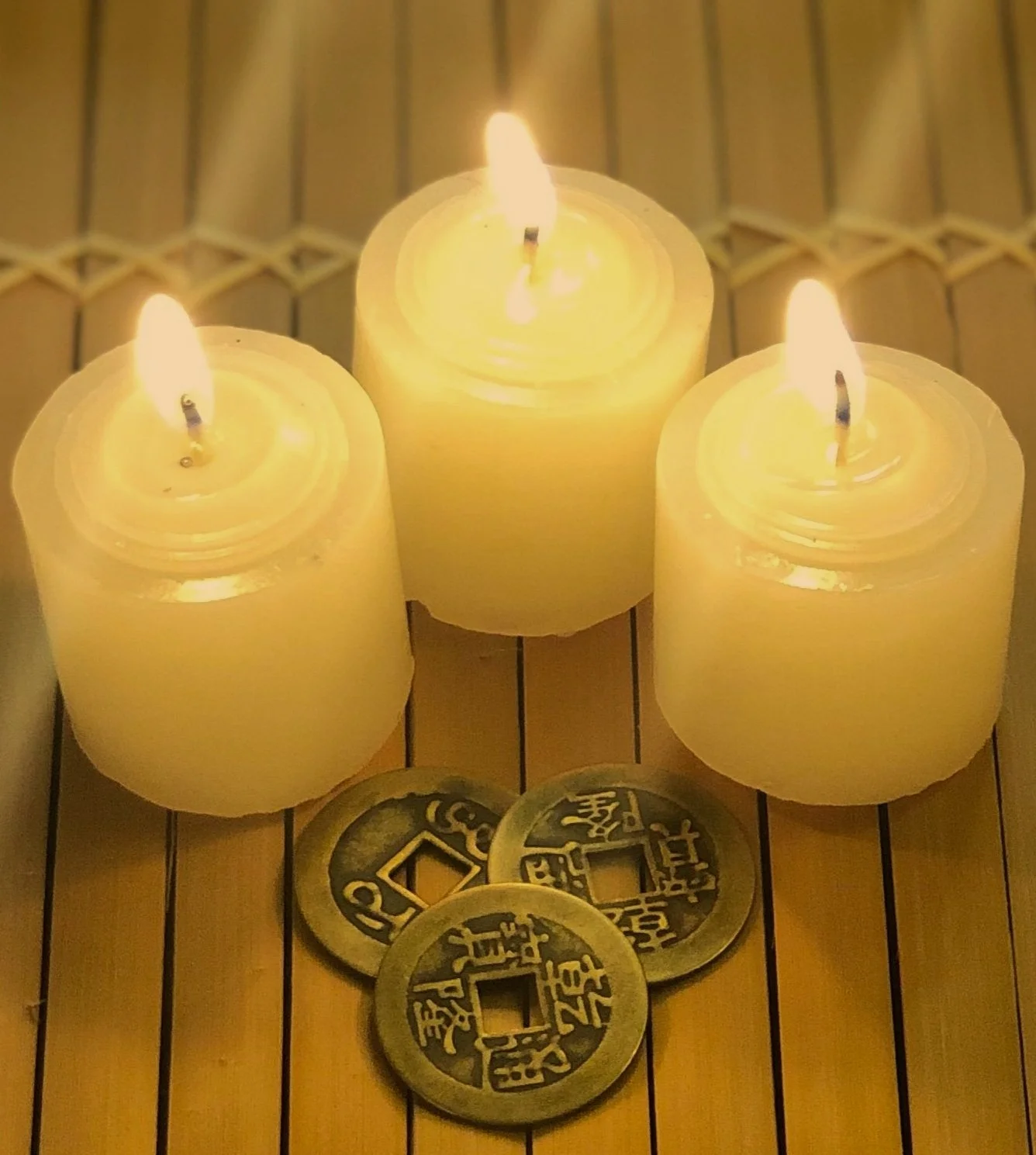 A beautiful candle lit image featuring I Ching coins and candles, representing the calm and balanced wellness and divination architecture of Misa Barron's energy clearing and powerful supportive services.