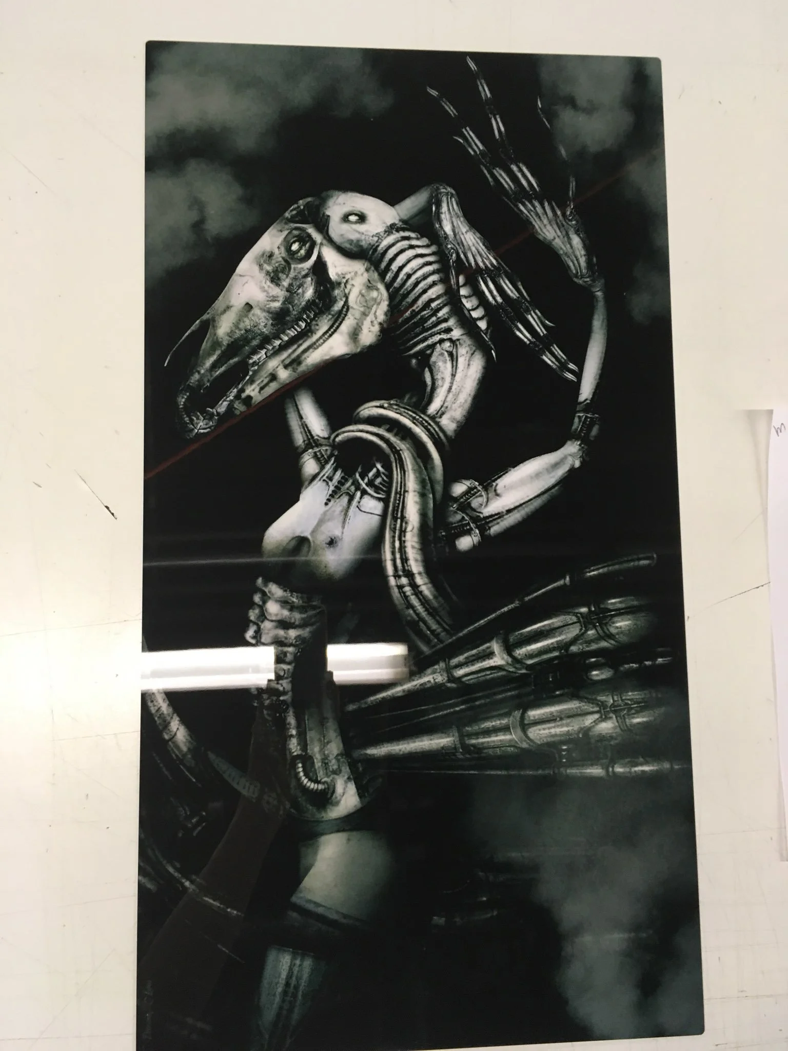 Black and white illustration of a robotic dragon with a skeletal head, set against a cloudy sky background.
