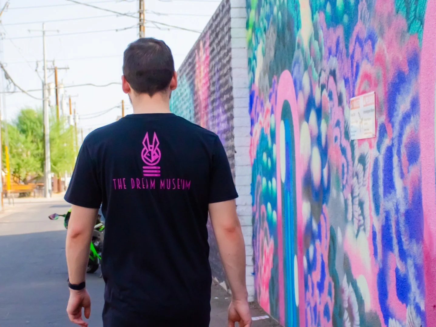 Person walking past colorful mural at The Dreim Museum